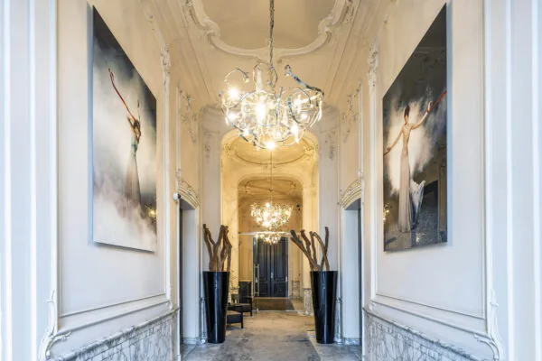 Luxe gang in een grachtenpand aan de Herengracht met kroonluchters, moderne kunst en marmeren lambrisering.