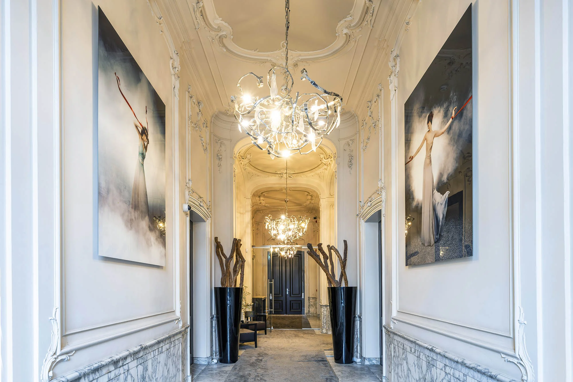 Luxe gang in een grachtenpand aan de Herengracht met kroonluchters, moderne kunst en marmeren lambrisering.