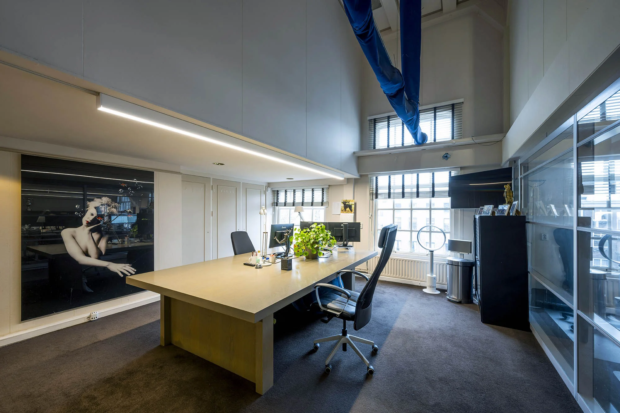 Modern kantoorinterieur aan de Herengracht met groot bureau, kunst aan de muur en veel natuurlijk licht.