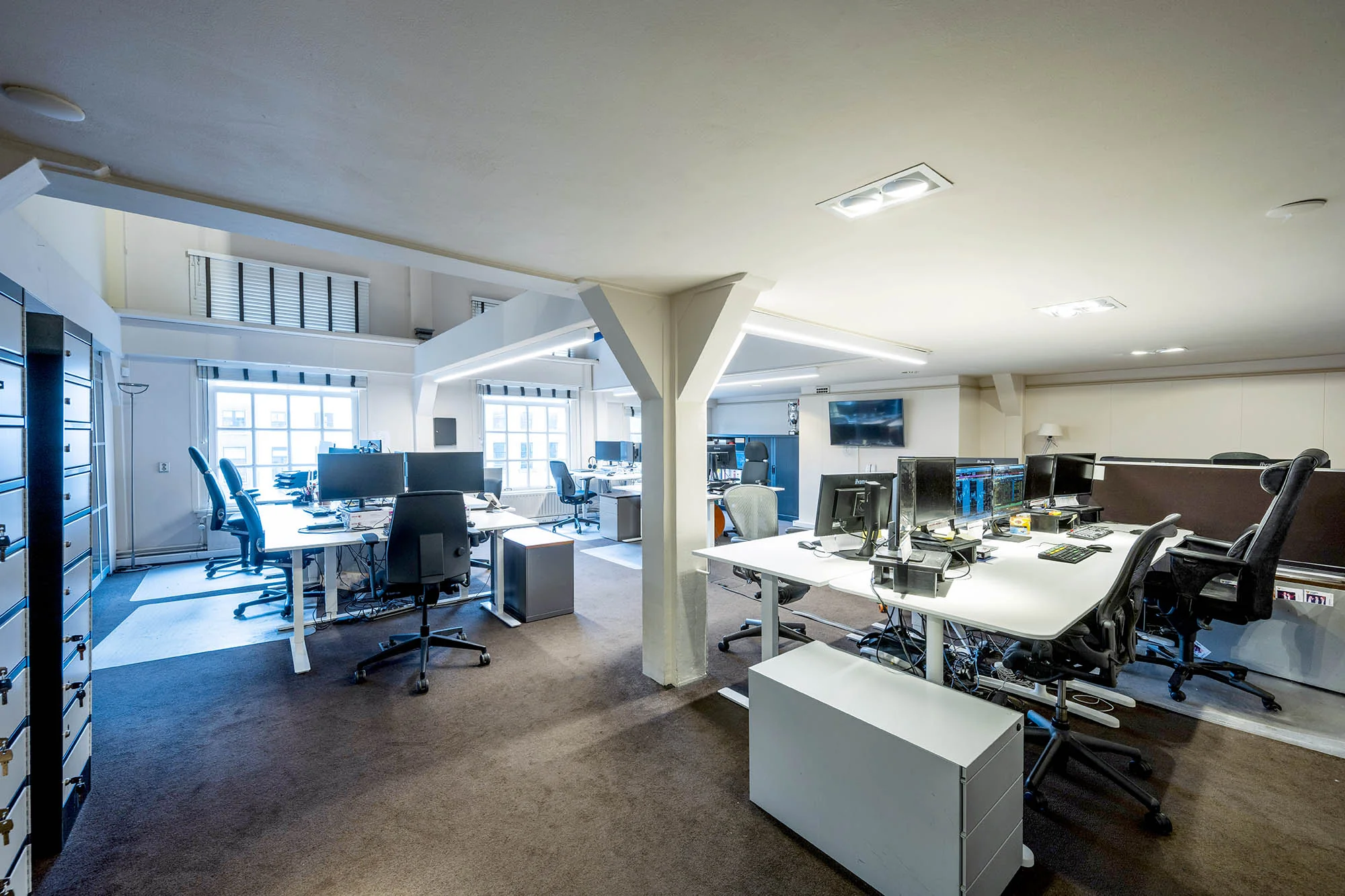 Modern open kantoor met meerdere bureaus, computerschermen en ergonomische stoelen aan de Herengracht.