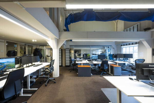 Modern kantoorpand aan de Herengracht met open werkplekken, bureaus en computerschermen.
