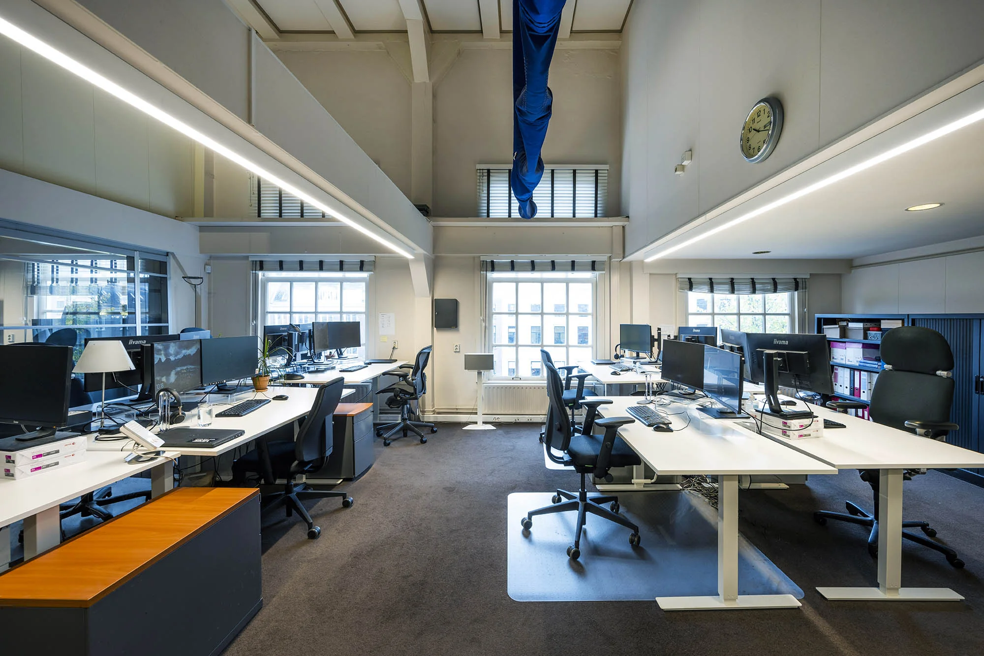 Moderne, open kantoorruimte aan de Herengracht met meerdere bureaus, computerschermen en ergonomische stoelen.