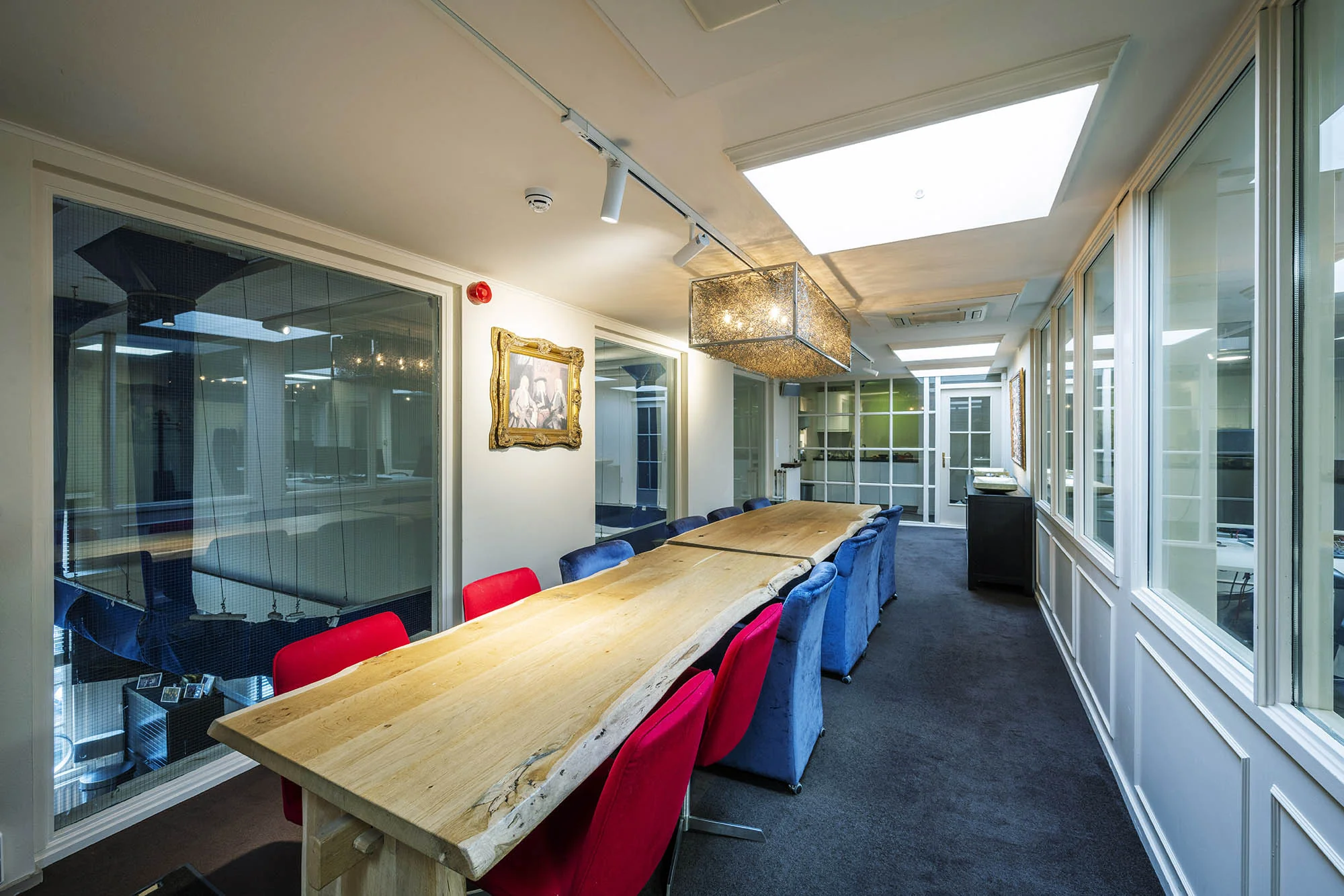 Vergaderruimte met een lange houten tafel, felgekleurde stoelen en moderne verlichting aan de Herengracht.