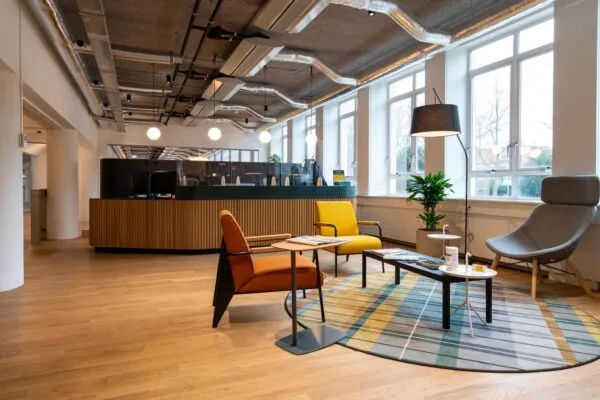 Moderne wachtruimte aan de Wassenaarseweg met designmeubels, houten vloer, grote ramen en een ontvangstbalie.