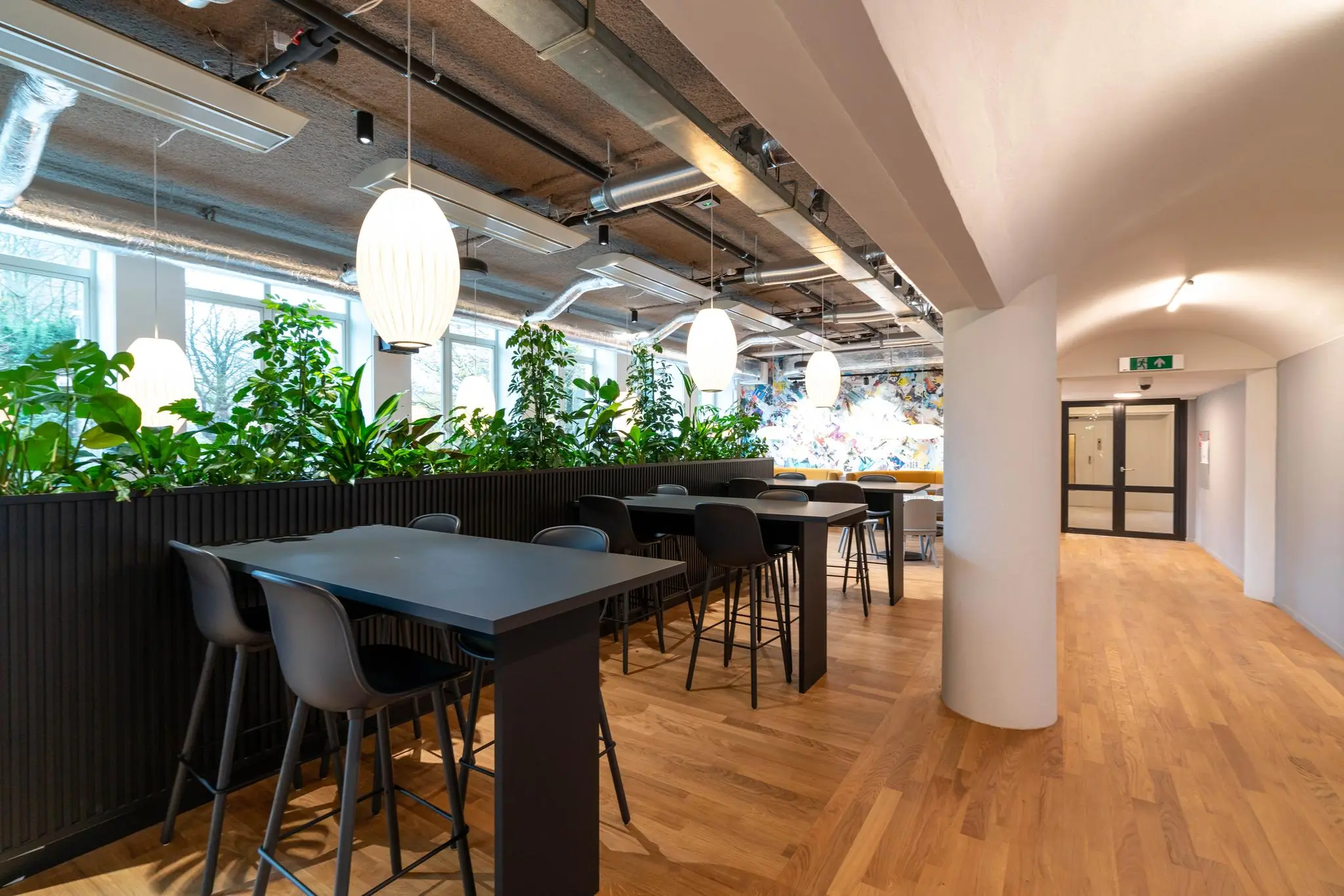 Moderne en sfeervolle kantoorruimte aan de Wassenaarseweg met hoge tafels, plantenbakken en hanglampen.