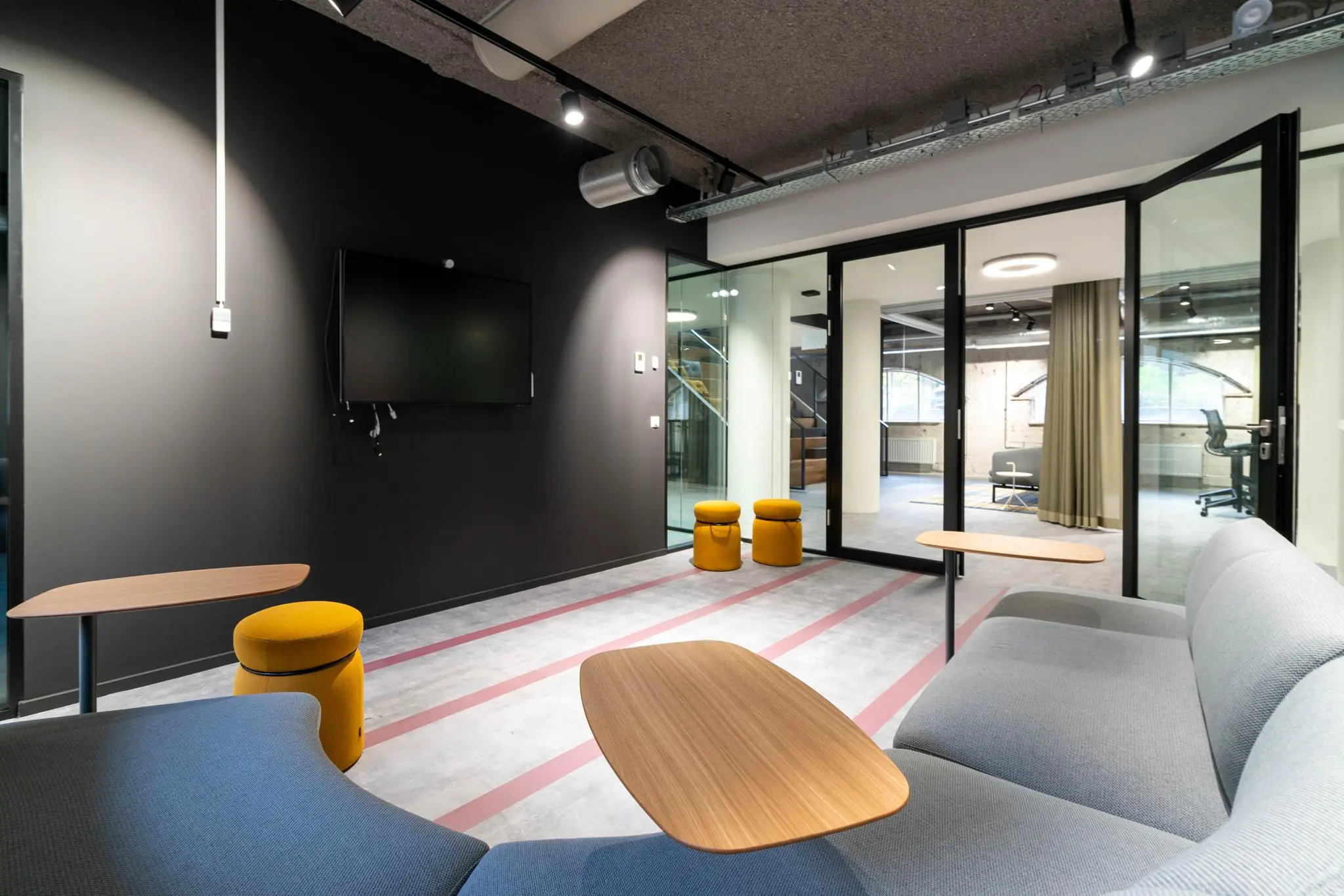 Moderne vergaderruimte aan de Wassenaarseweg met grijze wanden, glazen deuren, een flatscreen en eigentijdse meubels.