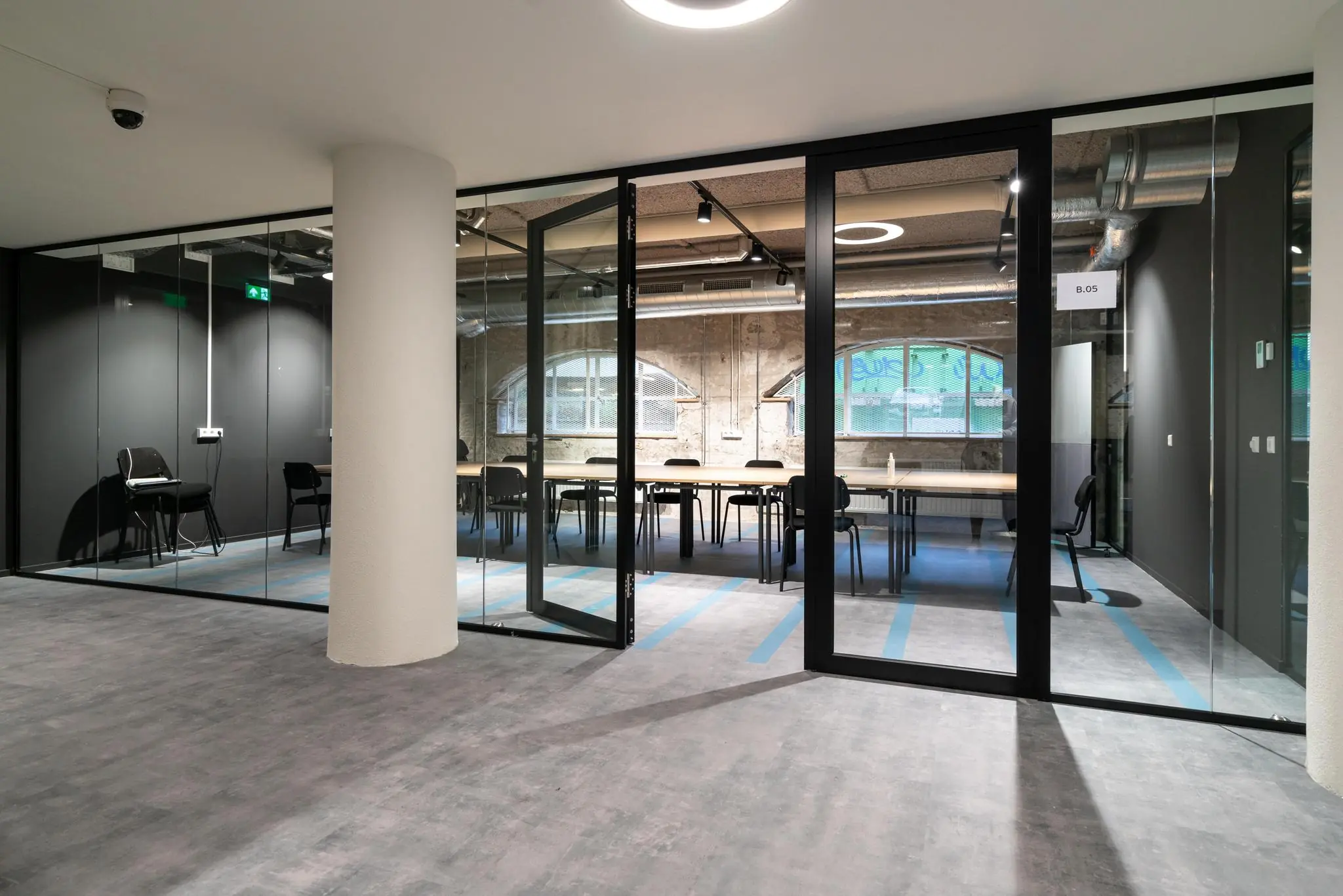 Moderne vergaderruimte aan de Wassenaarseweg met glazen wanden, industriële details en een lange tafel met stoelen.