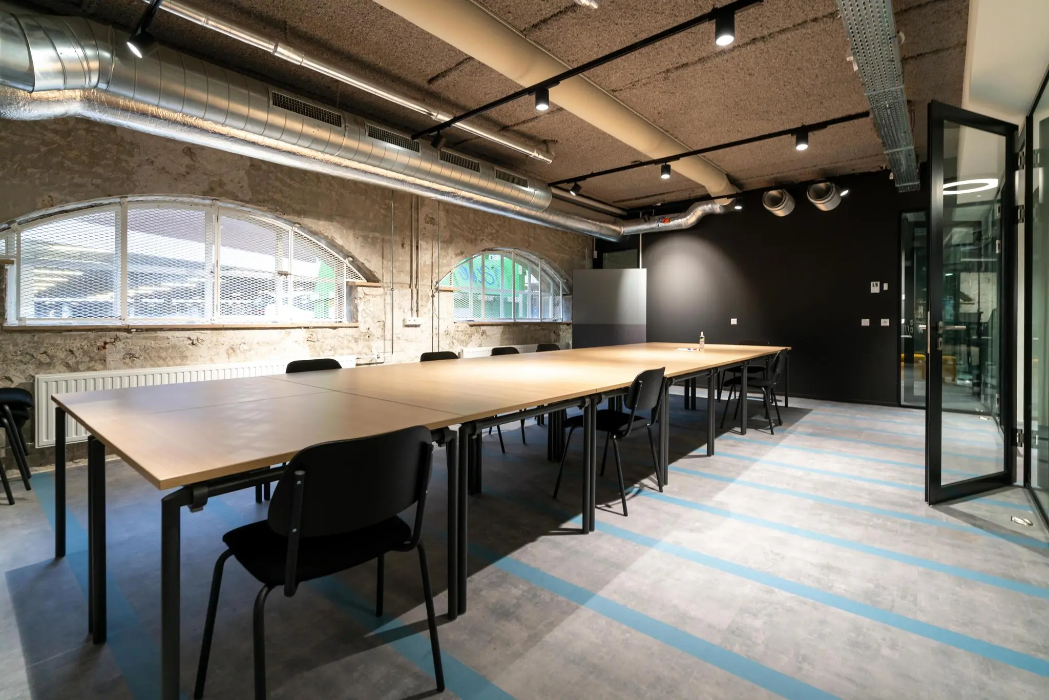 Moderne vergaderruimte aan de Wassenaarseweg met industriële uitstraling, grote houten tafels en zwarte stoelen.