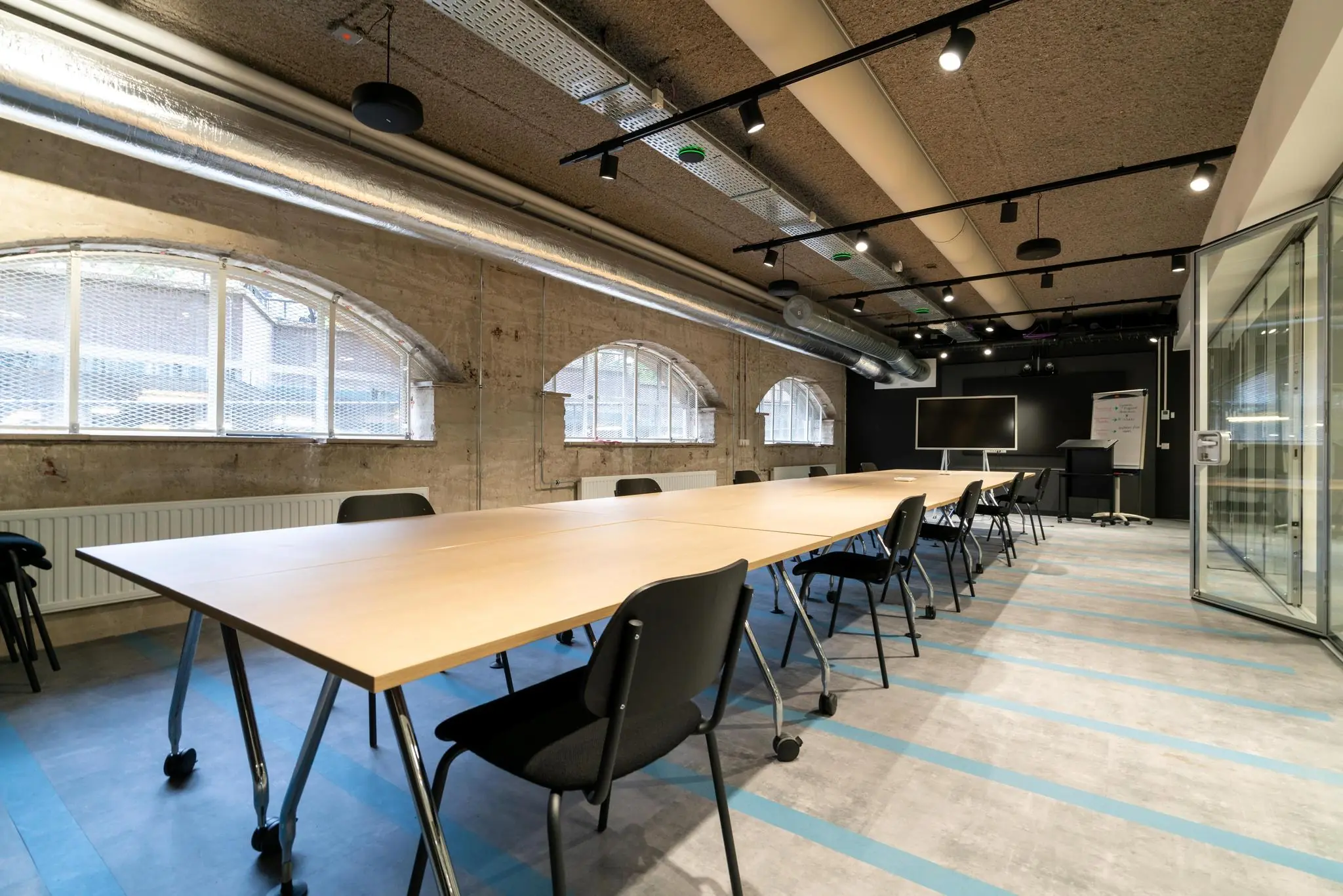 Moderne vergaderruimte aan de Wassenaarseweg met lange tafels, stoelen, glazen wand en grote ramen met boogvorm.