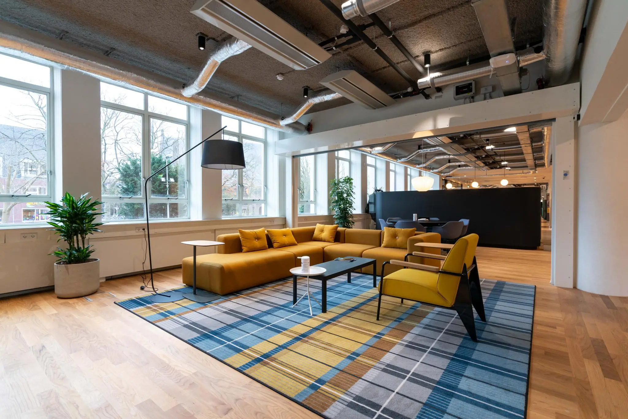 Modern ingerichte loungeruimte in een kantoorpand aan de Wassenaarseweg met gele zitmeubels, designverlichting en grote ramen.