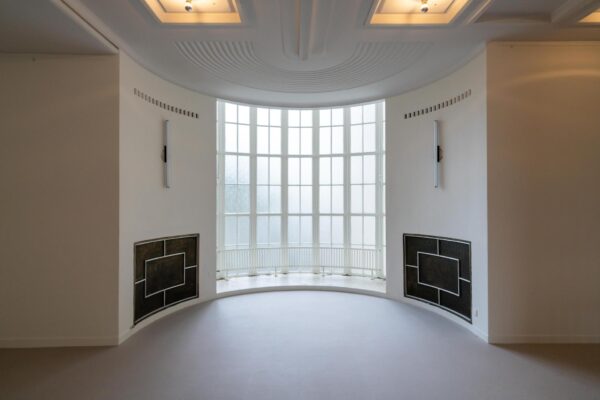 Lichte, ronde erker met grote raampartij in een modernistische kamer aan de Wassenaarseweg.