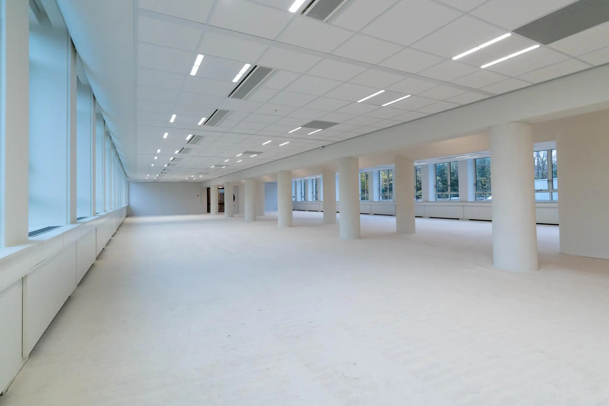 Licht en ruim kantoorinterieur aan de Wassenaarseweg met grote ramen en witte pilaren.
