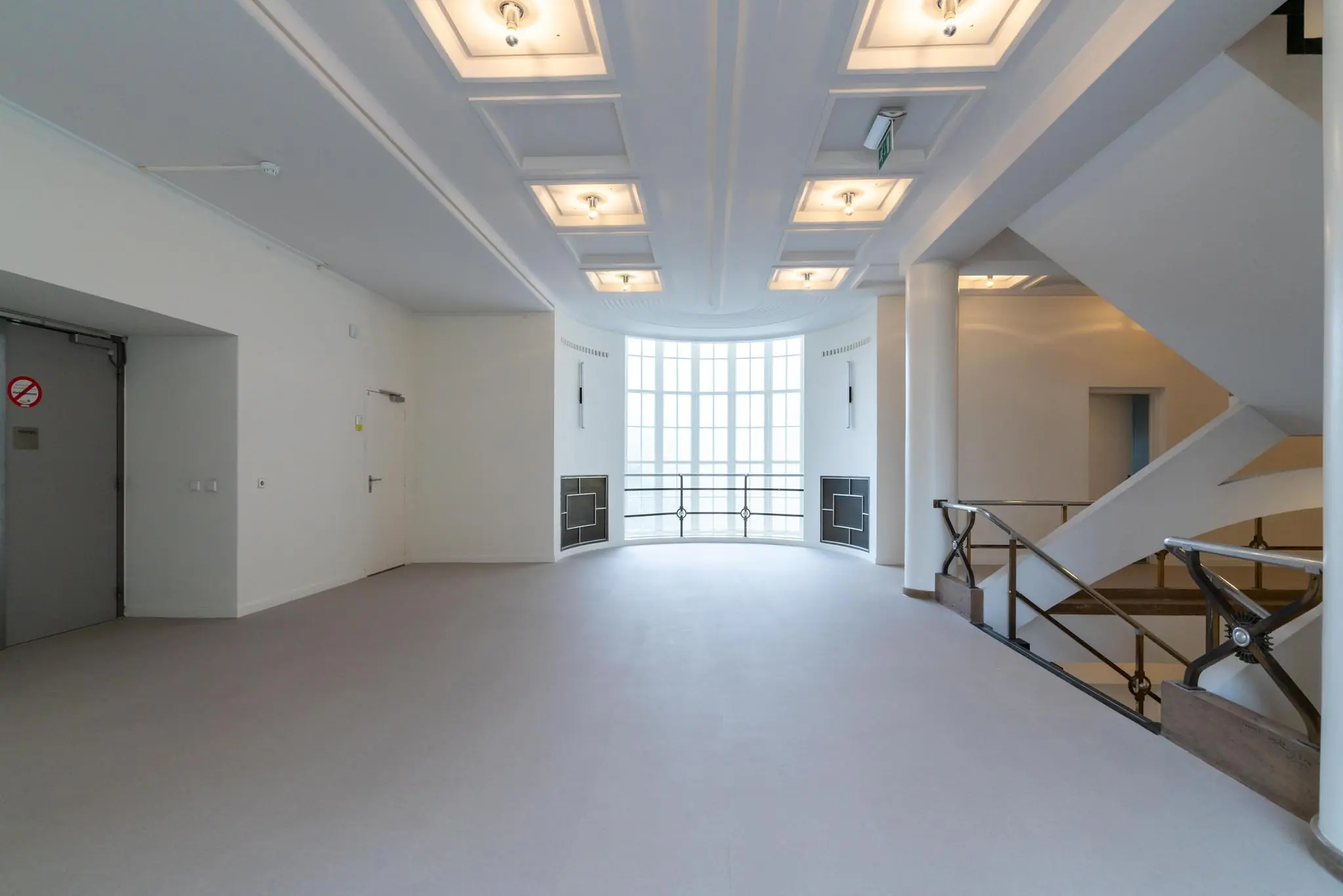 Lichte en moderne hal met grote raampartij, trappenhuis en verlichte plafondpanelen aan de Wassenaarseweg.
