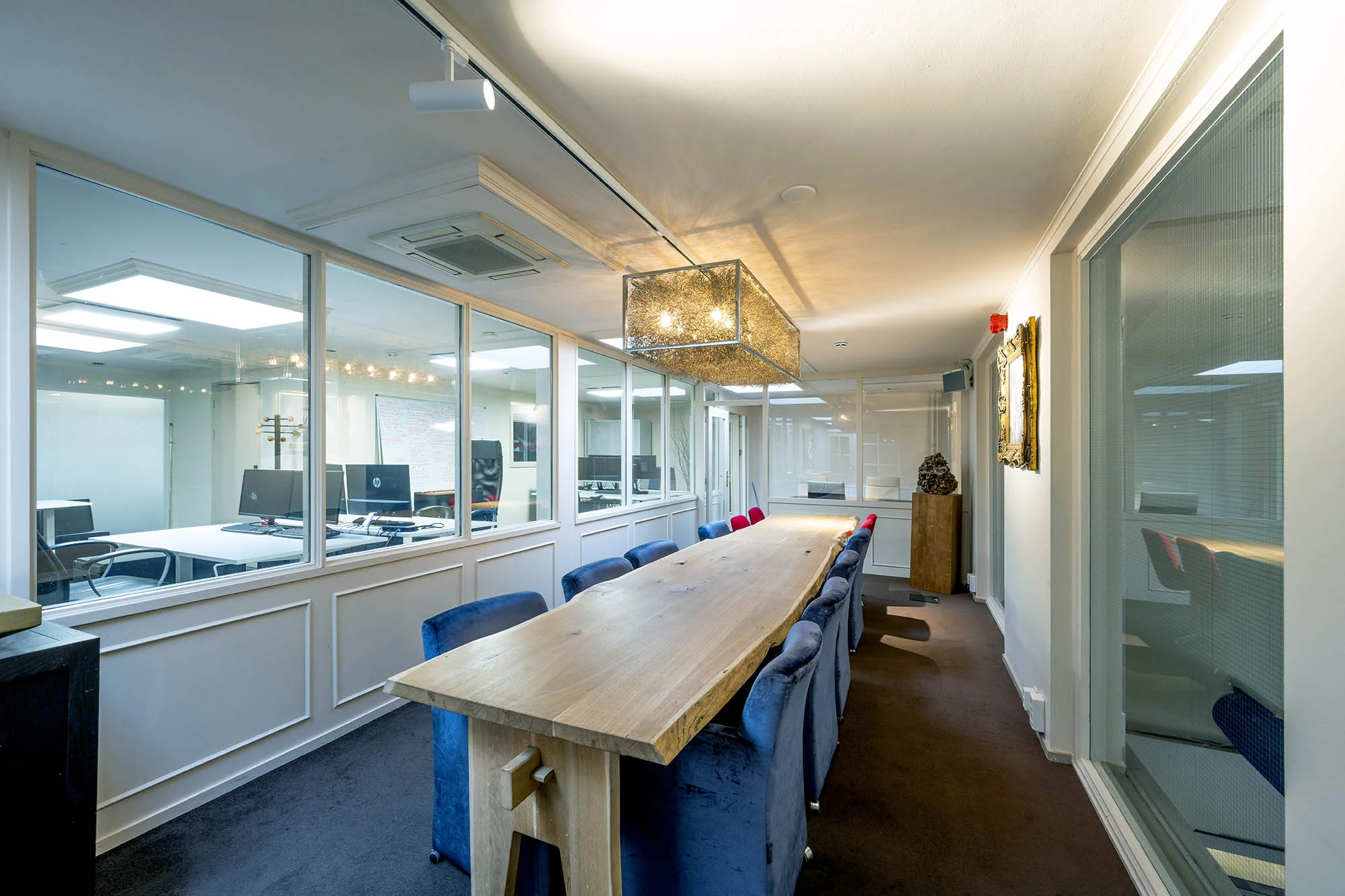 Vergaderruimte met een lange houten tafel, blauwe stoelen en glazen wanden aan de Herengracht.