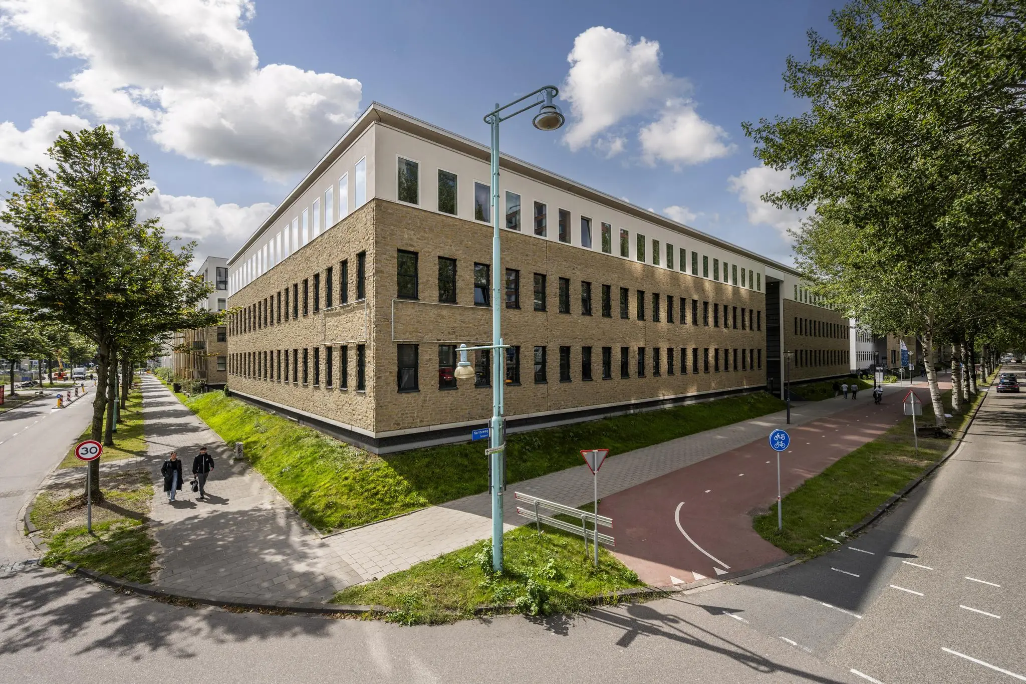 Modern kantoorgebouw aan de Naritaweg in Amsterdam met bakstenen gevel en aangrenzend fietspad.