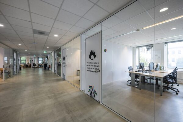 Moderne kantoorruimte aan de Naritaweg met glazen wanden, werkplekken en inspirerende muurteksten.