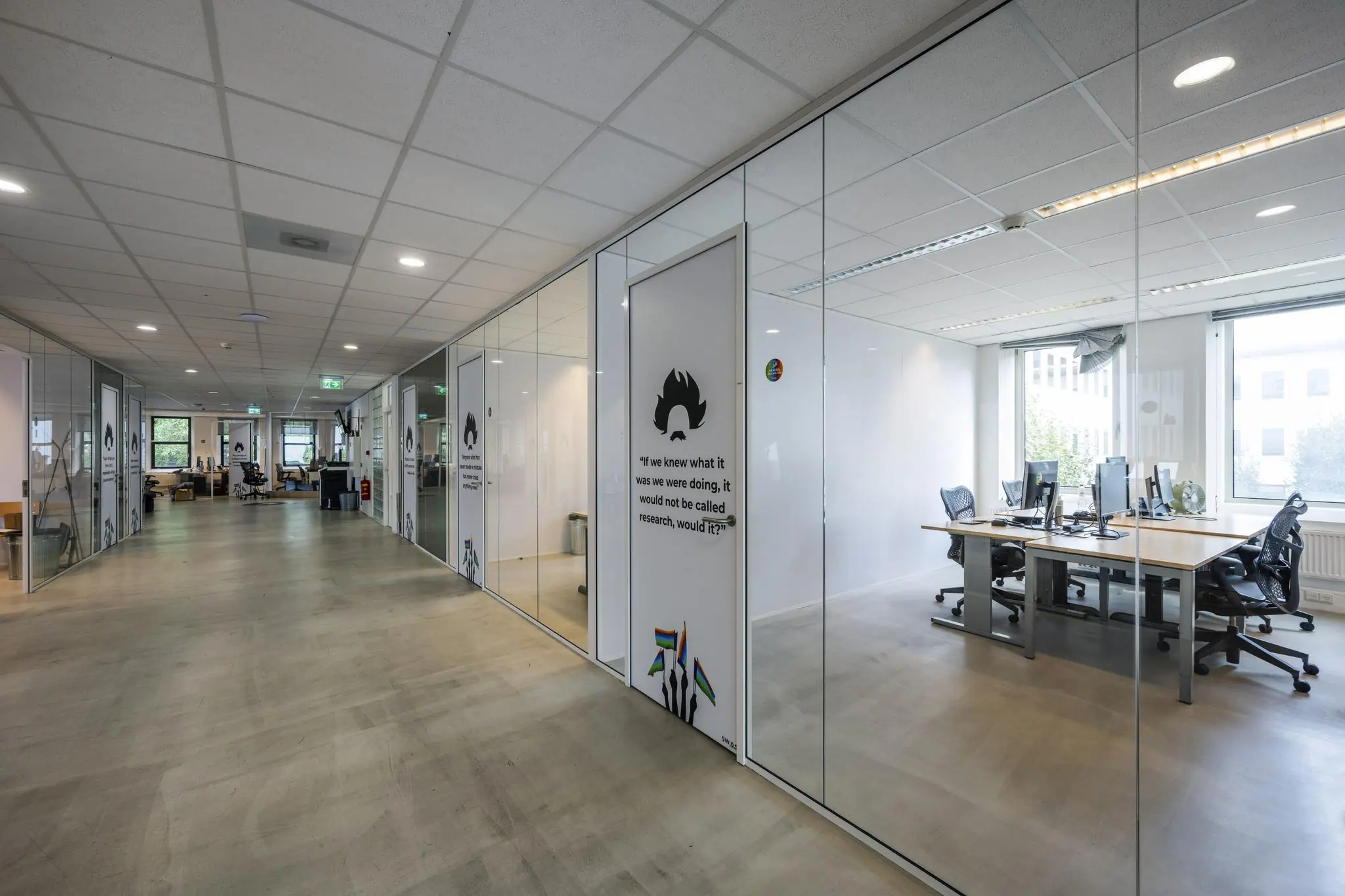 Moderne kantoorruimte aan de Naritaweg met glazen wanden, werkplekken en inspirerende muurteksten.