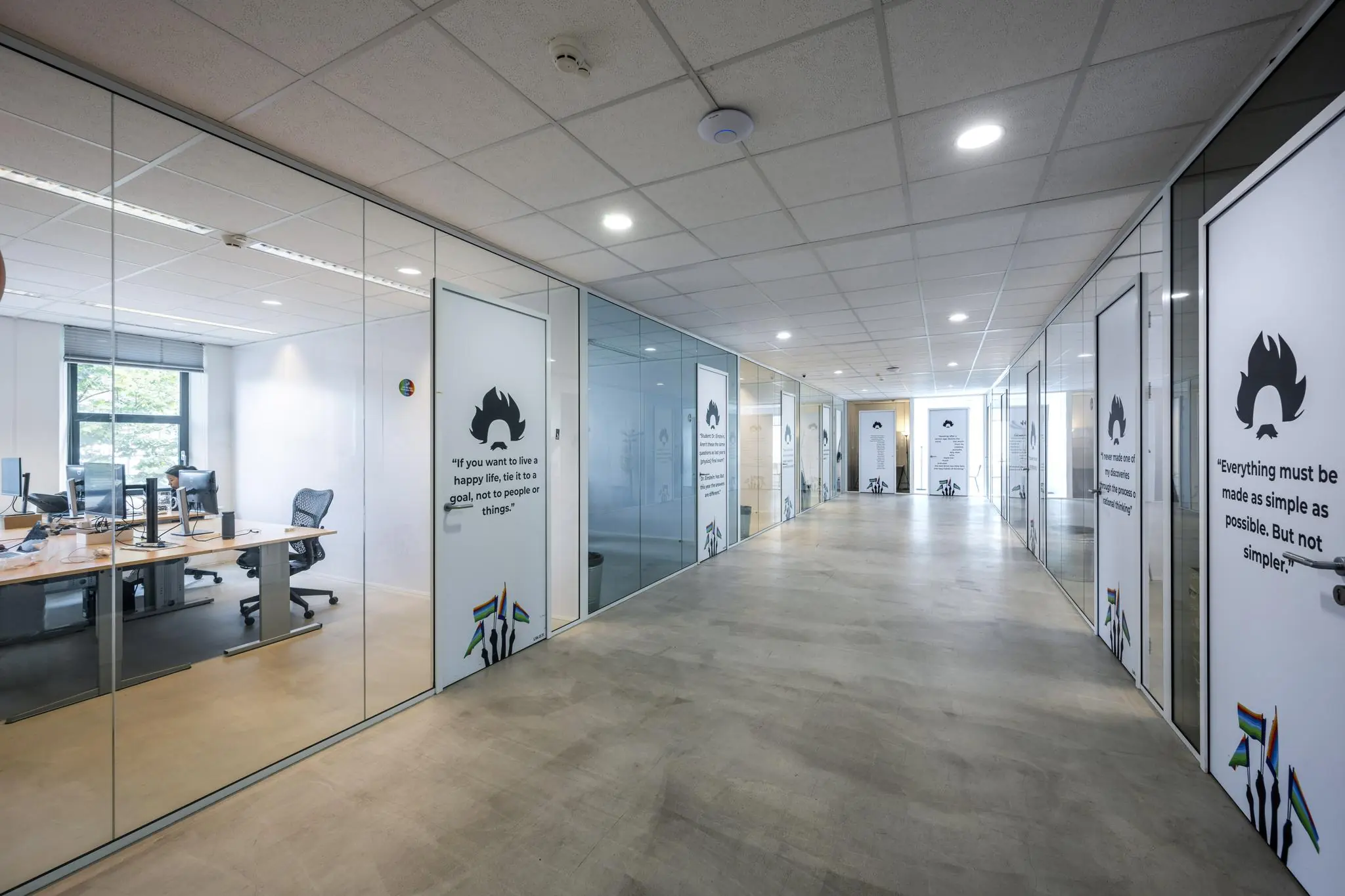 Moderne kantoorruimte aan de Naritaweg met glazen wanden, inspirerende citaten op de deuren en zicht op meerdere werkplekken.