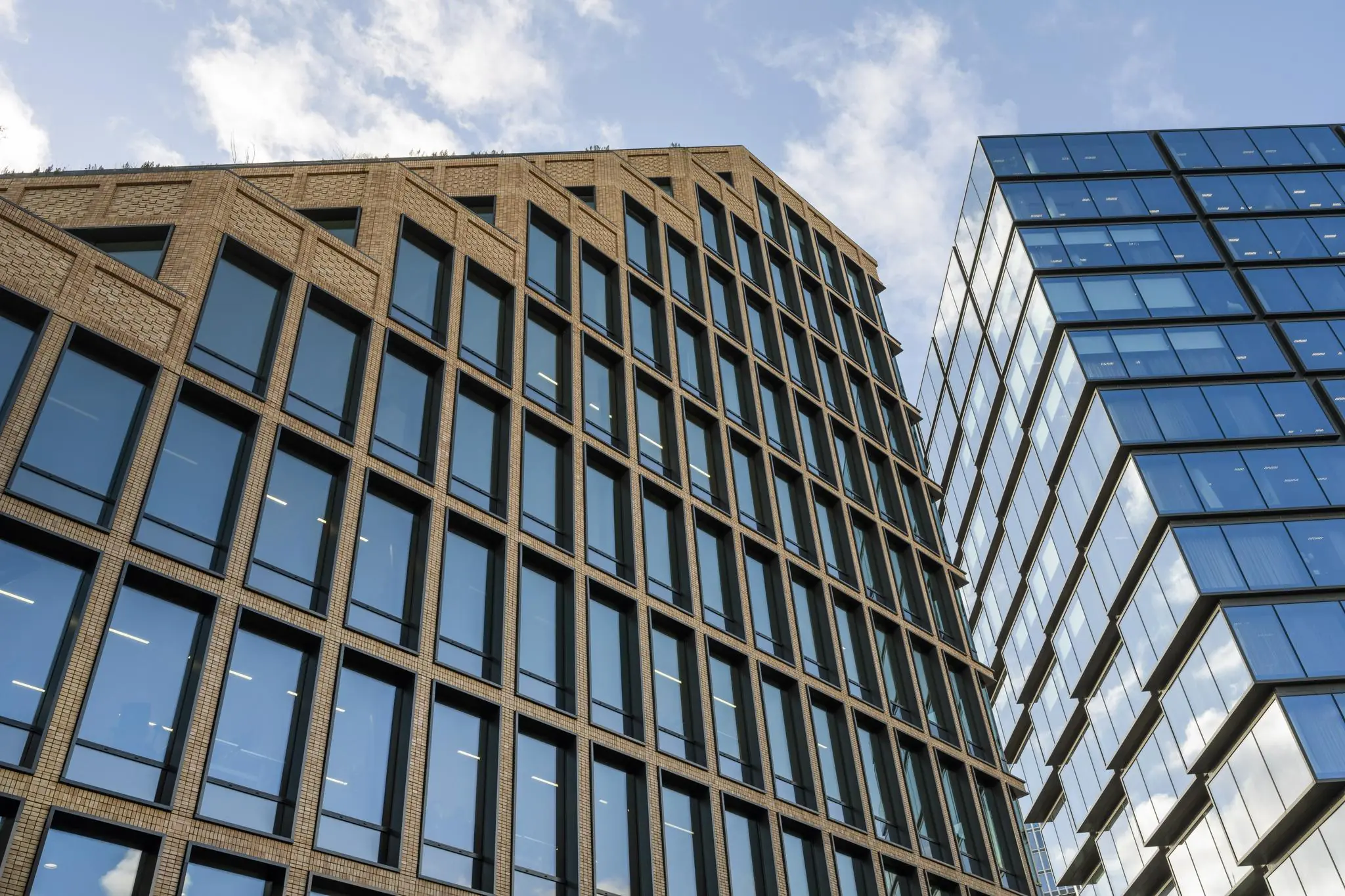 Twee moderne kantoorgebouwen aan de Gelrestraat met weerspiegelende ramen tegen een blauwe lucht.