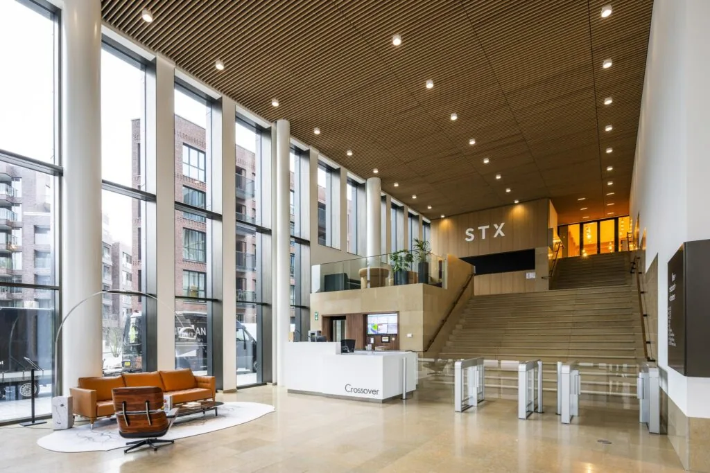 Moderne, lichte entreehal van het kantoorgebouw aan de Gelrestraat met ontvangstbalie, zitgedeelte en brede trap naar STX.