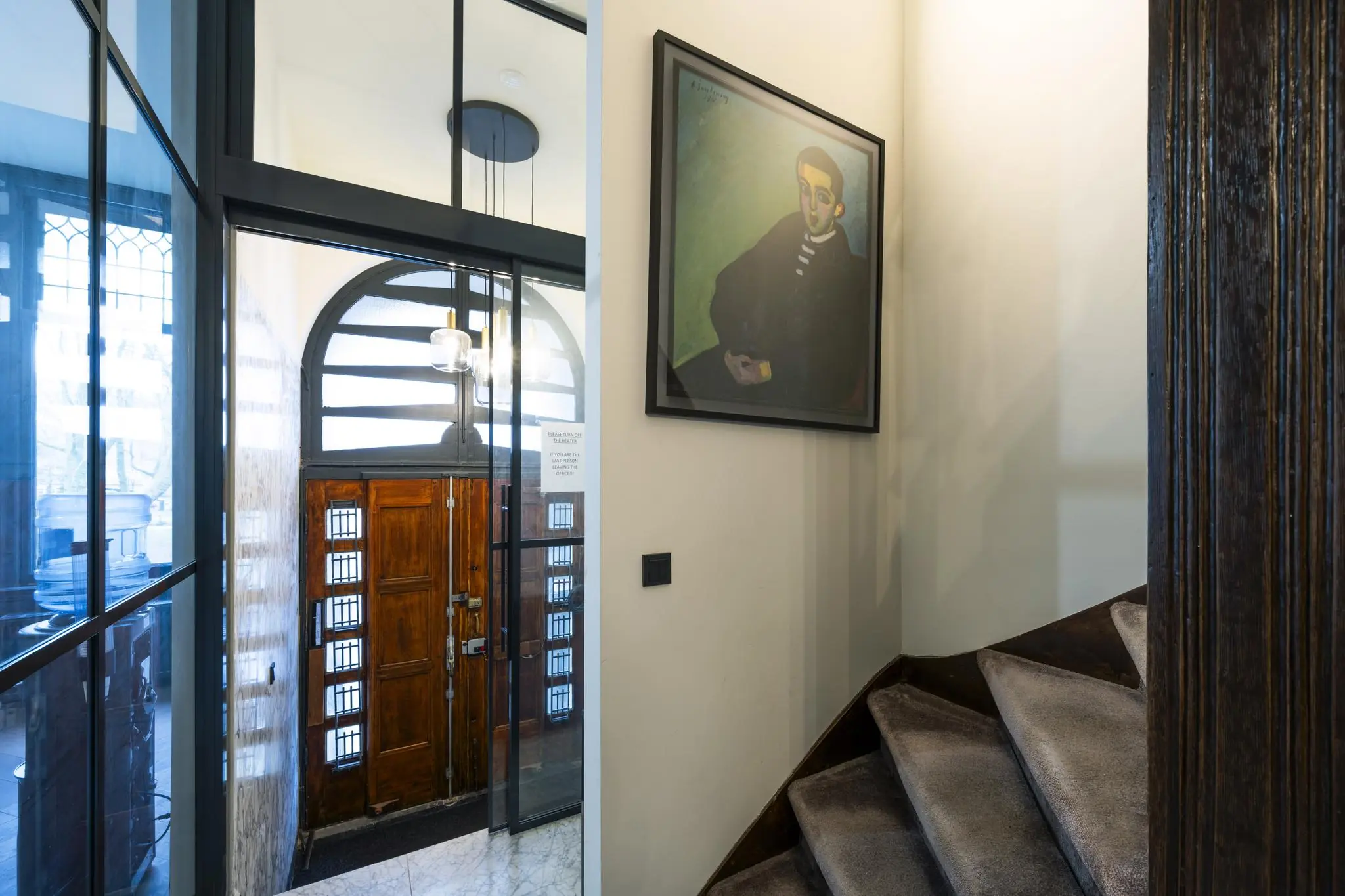 Entreehal met houten voordeur, marmeren vloer, trap met tapijt en een schilderij aan de muur in het Eerste Weteringplantsoen.