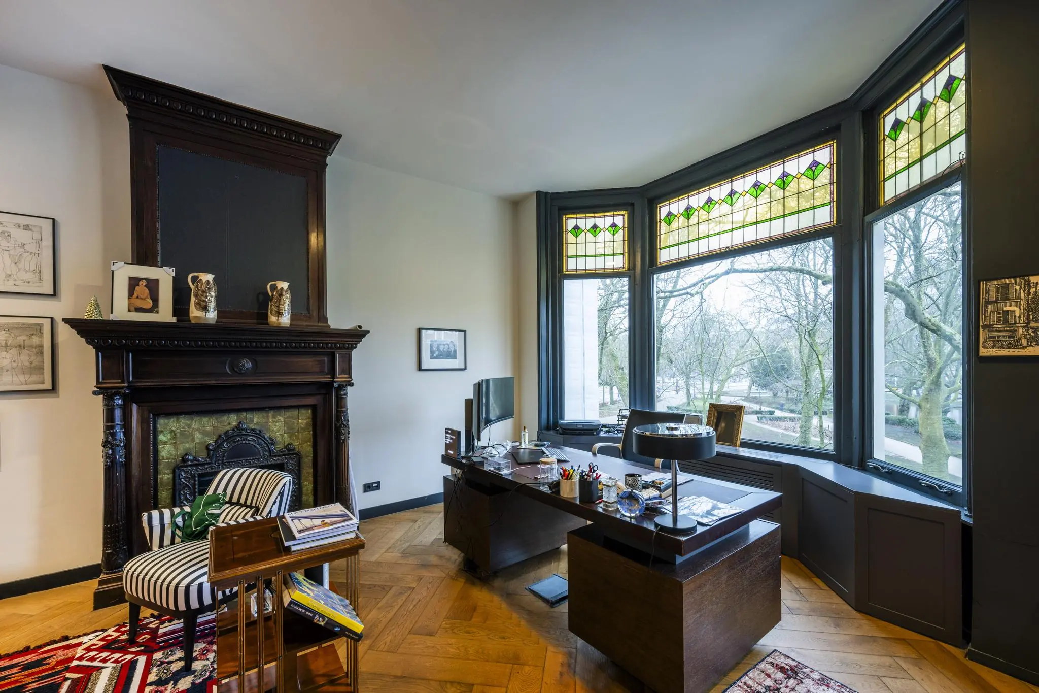 Stijlvol kantoor met houten vloer, open haard, glas-in-loodramen en uitzicht op het Eerste Weteringplantsoen.