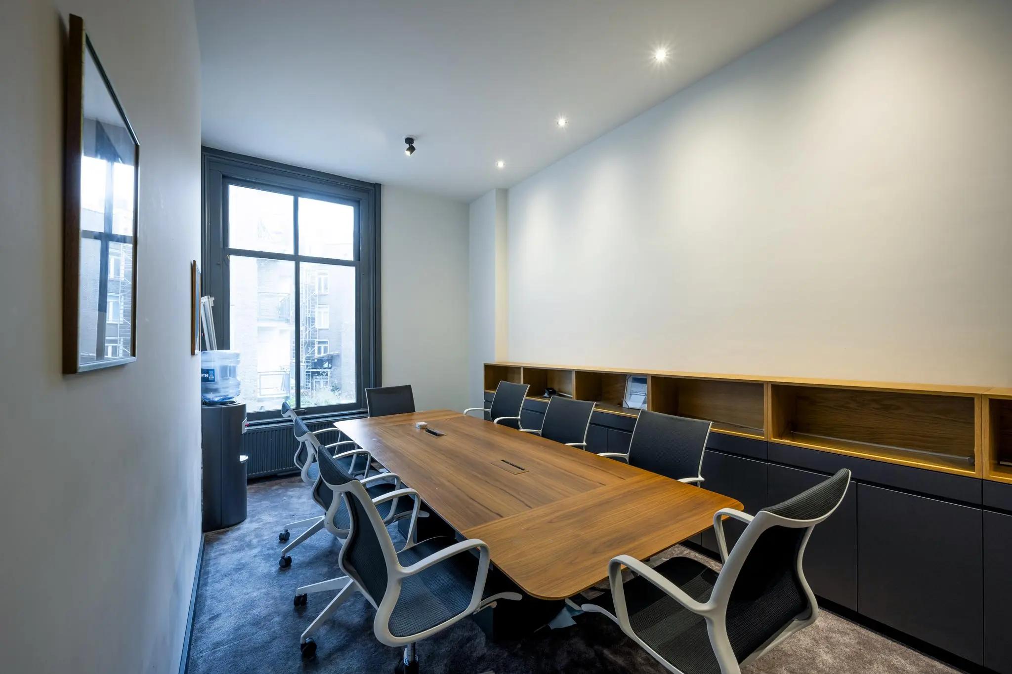 Vergaderruimte met een houten tafel, moderne stoelen en een groot raam in het Eerste Weteringplantsoen.