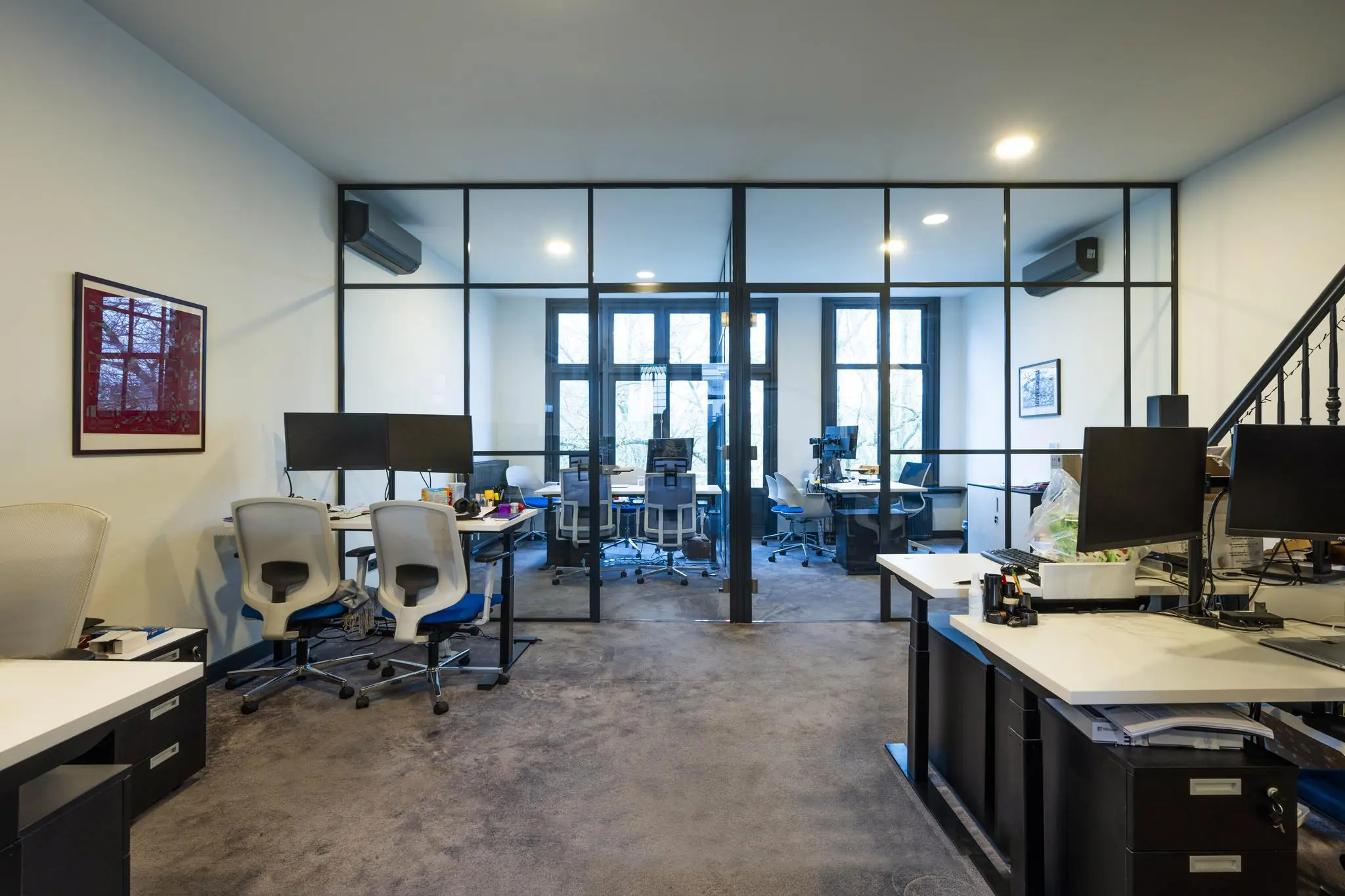 Modern kantoorinterieur aan het Eerste Weteringplantsoen met bureaus, computerschermen en glazen vergaderruimte.