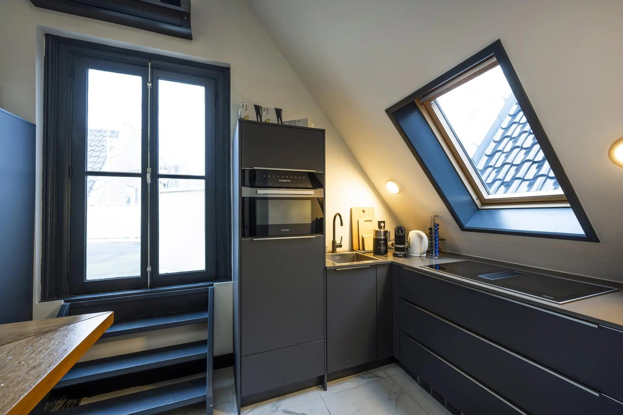 Moderne keuken in een zolderruimte met schuine wanden en dakramen aan het Eerste Weteringplantsoen.
