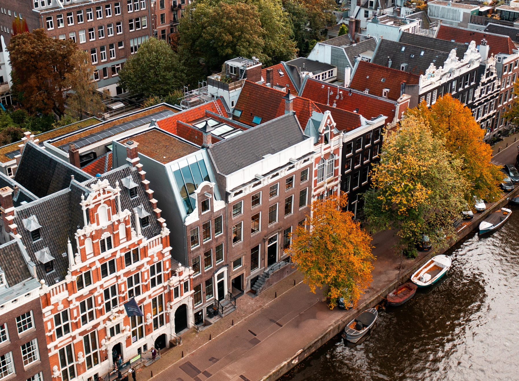 Luchtfoto van historische grachtenpanden en herfstbomen langs de Keizersgracht in Amsterdam.