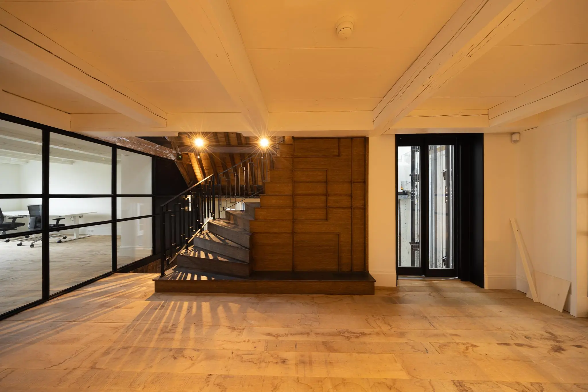 Modern kantoorinterieur aan de Keizersgracht met houten trap, glazen wand en houten vloer.