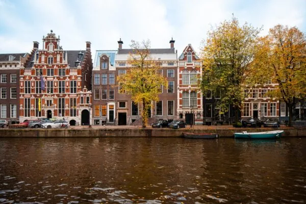 Gevels van historische panden aan de Keizersgracht in Amsterdam met herfstkleuren en boten in de gracht.