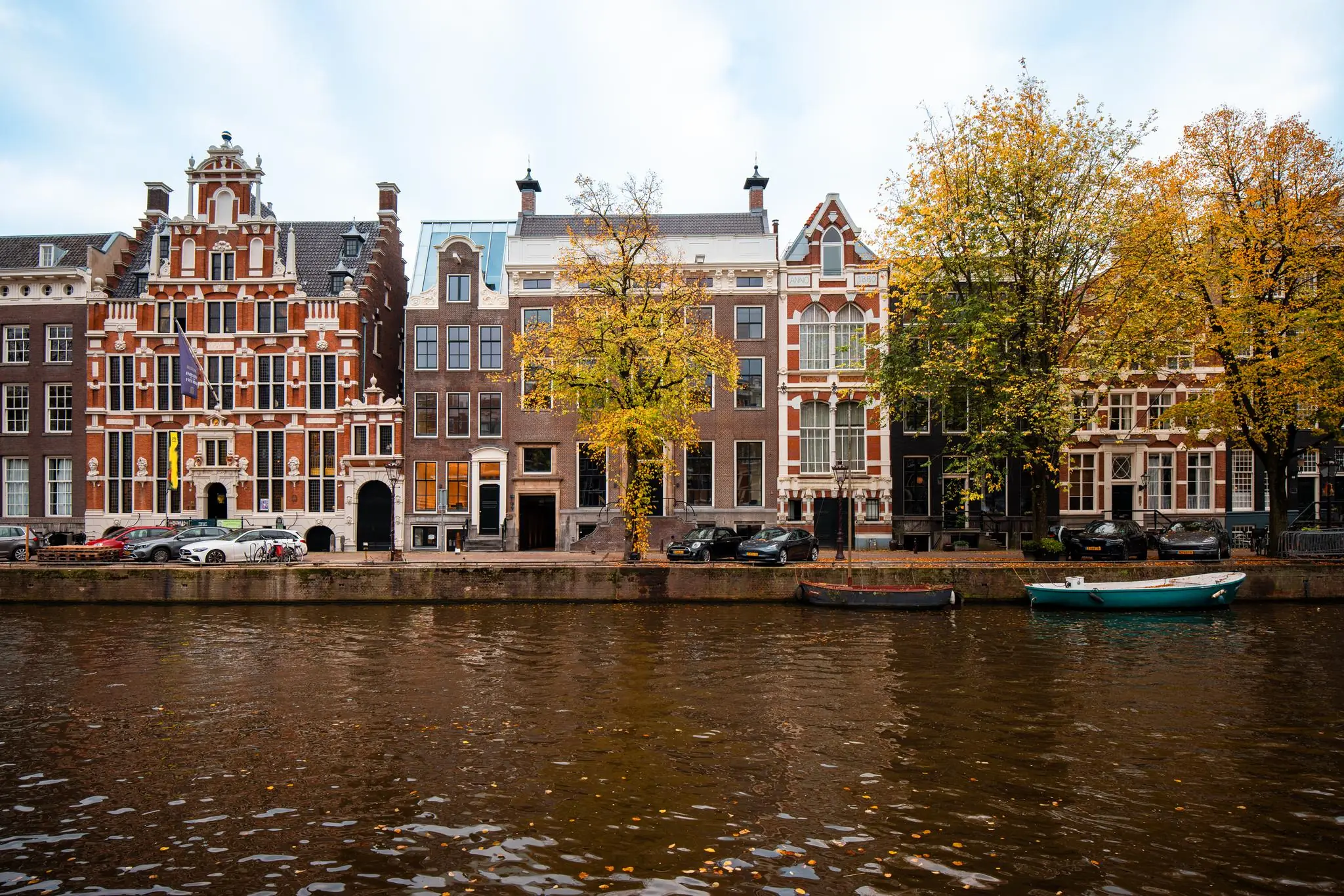 Gevels van historische panden aan de Keizersgracht in Amsterdam met herfstkleuren en boten in de gracht.