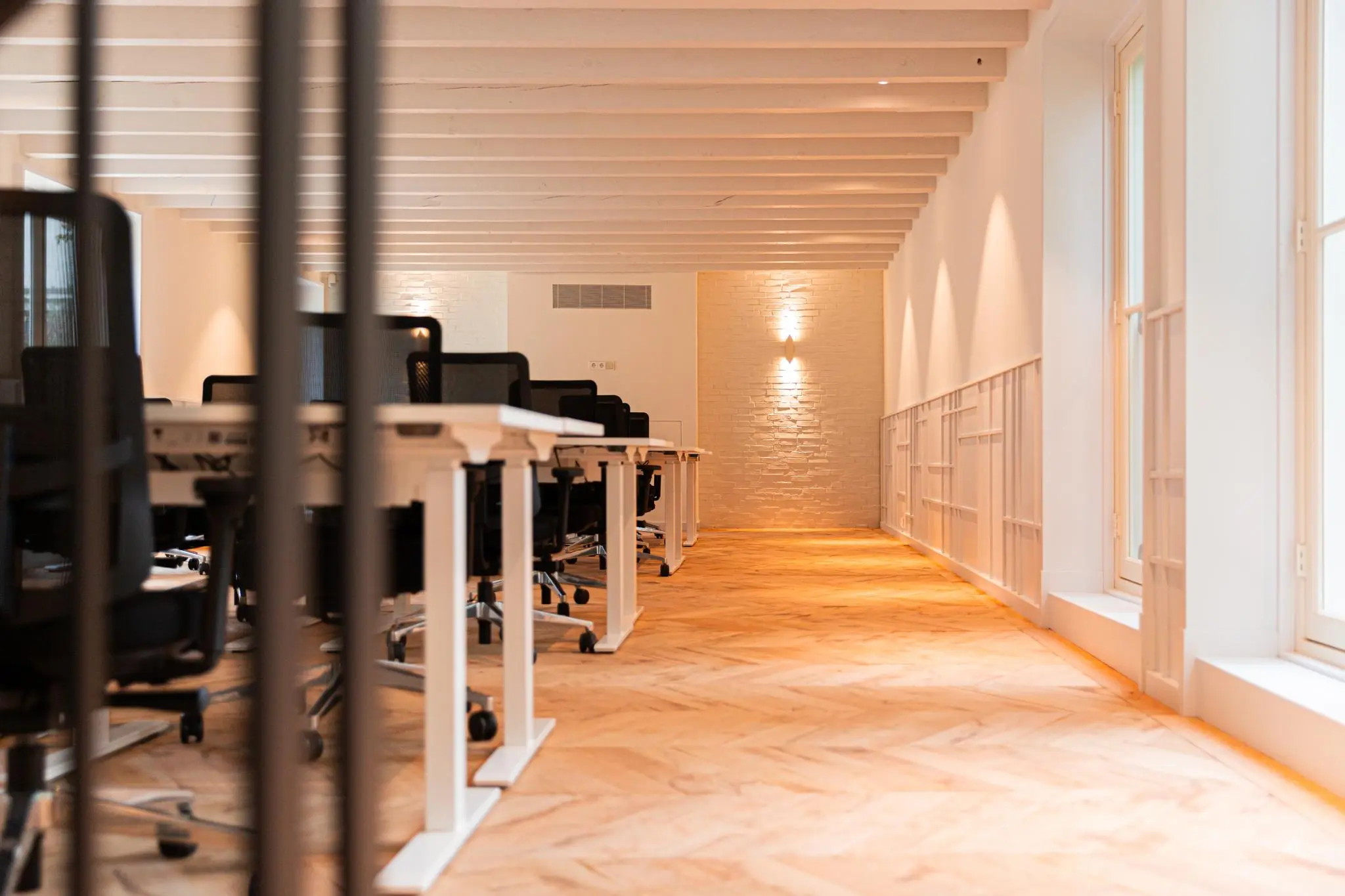 Licht en modern kantoorinterieur aan de Keizersgracht met rijen bureaus en zwarte bureaustoelen.