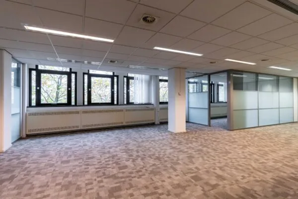 Leeg kantoorpand aan de Bezuidenhoutseweg met systeemplafond, tapijtvloer en glazen scheidingswanden.