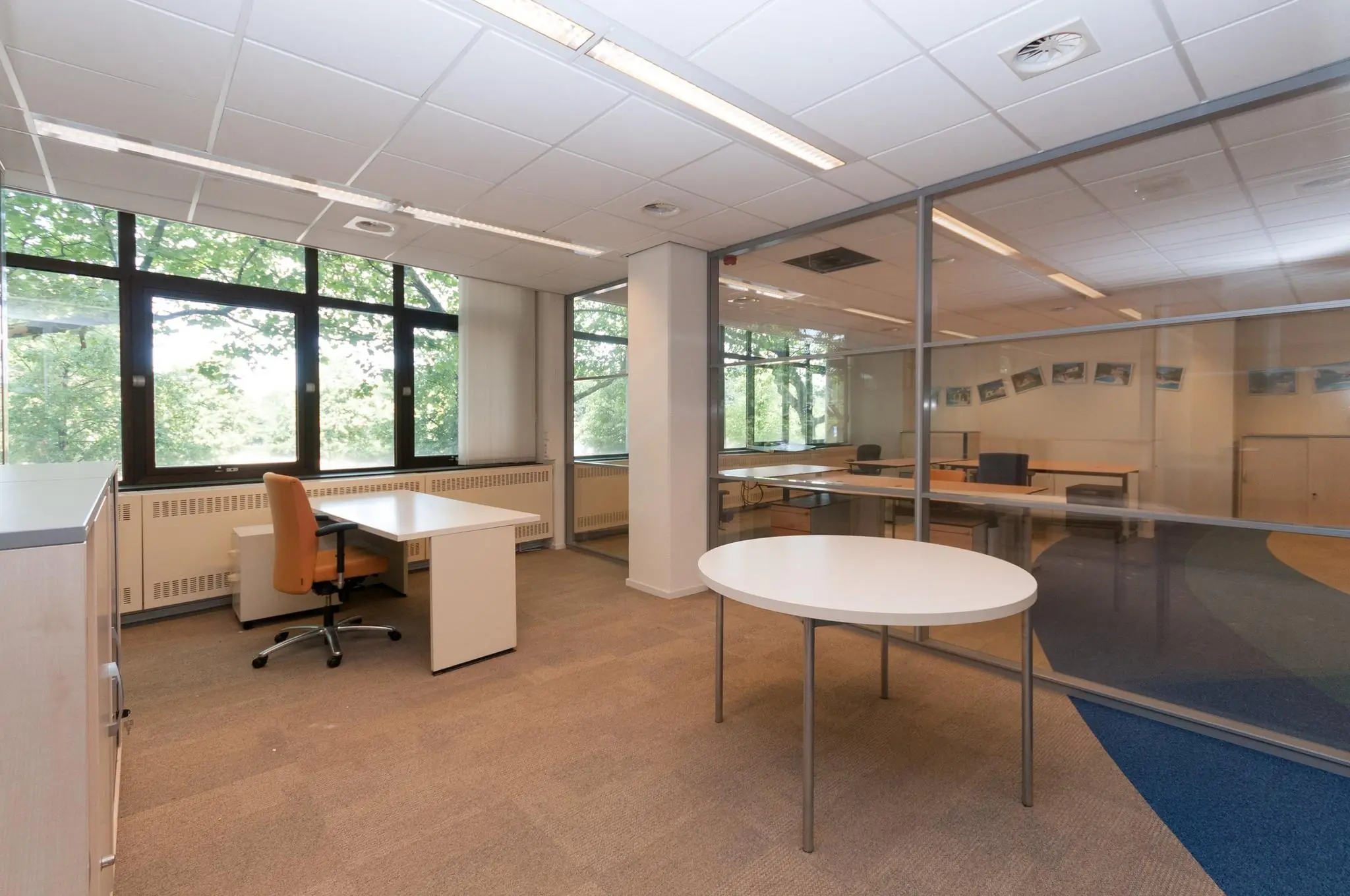 Licht en ruim kantoorpand aan de Bezuidenhoutseweg met grote ramen en meerdere werkplekken.