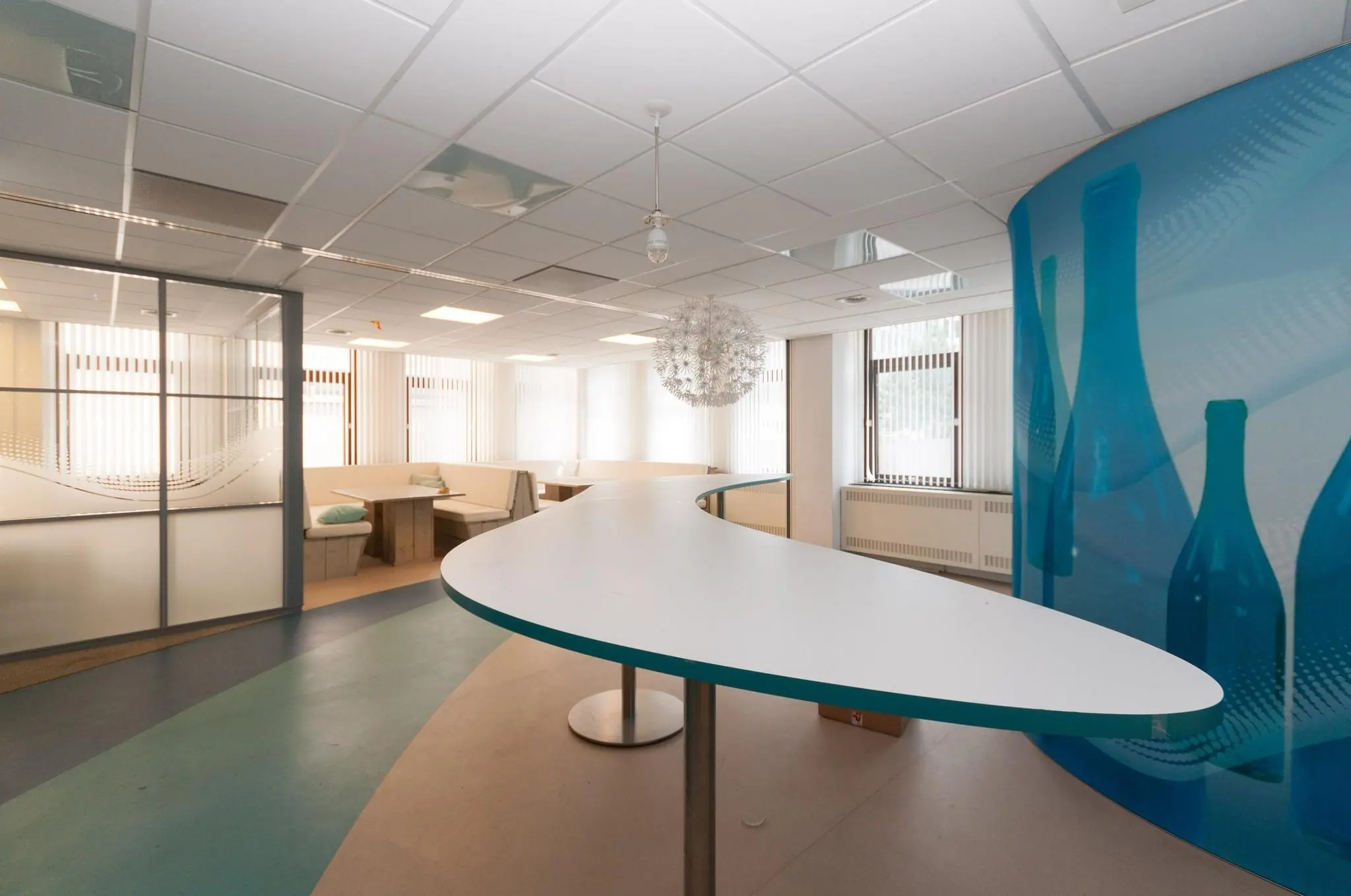 Kantoorruimte aan de Bezuidenhoutseweg met een gebogen witte tafel, zithoeken en modern interieur.