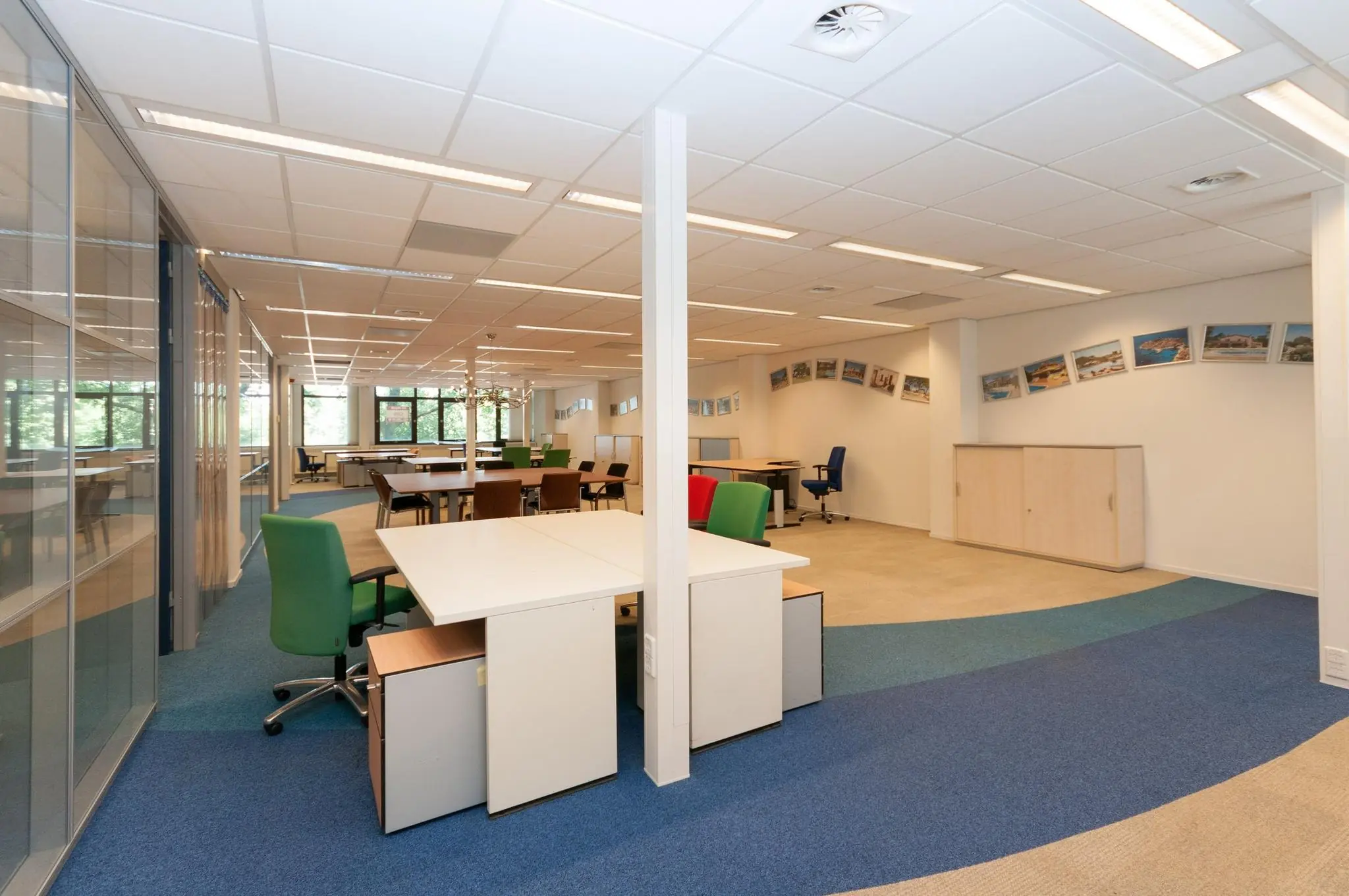 Modern en open kantoorinterieur aan de Bezuidenhoutseweg met bureaus, kleurrijke stoelen en fotokunst aan de muur.