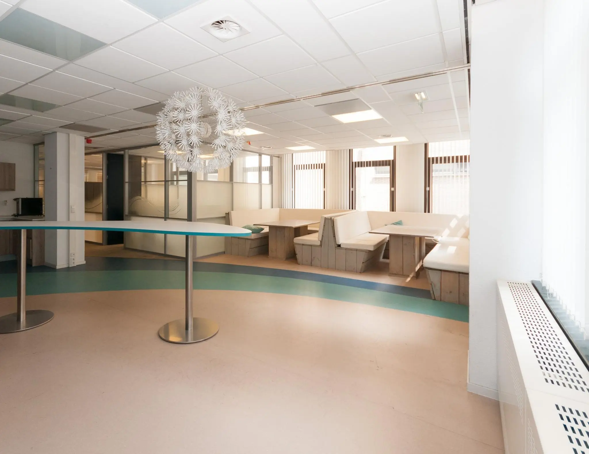 Moderne, licht ingerichte wachtruimte aan de Bezuidenhoutseweg met zithoeken en glazen scheidingswanden.