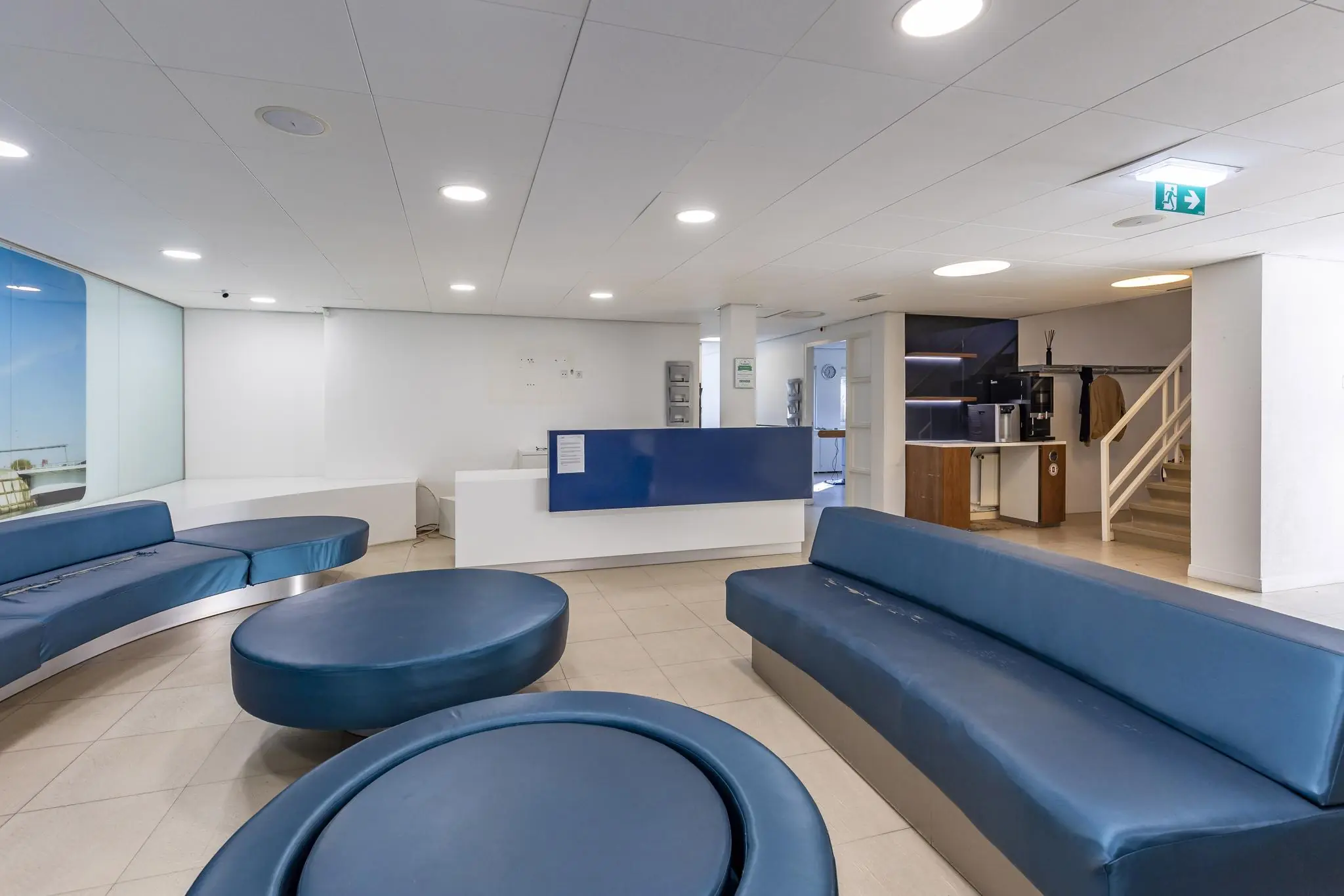 Moderne wachtruimte met blauwe zitbanken, een receptiebalie en een koffiehoek in een pand aan de 's-Gravenweg.