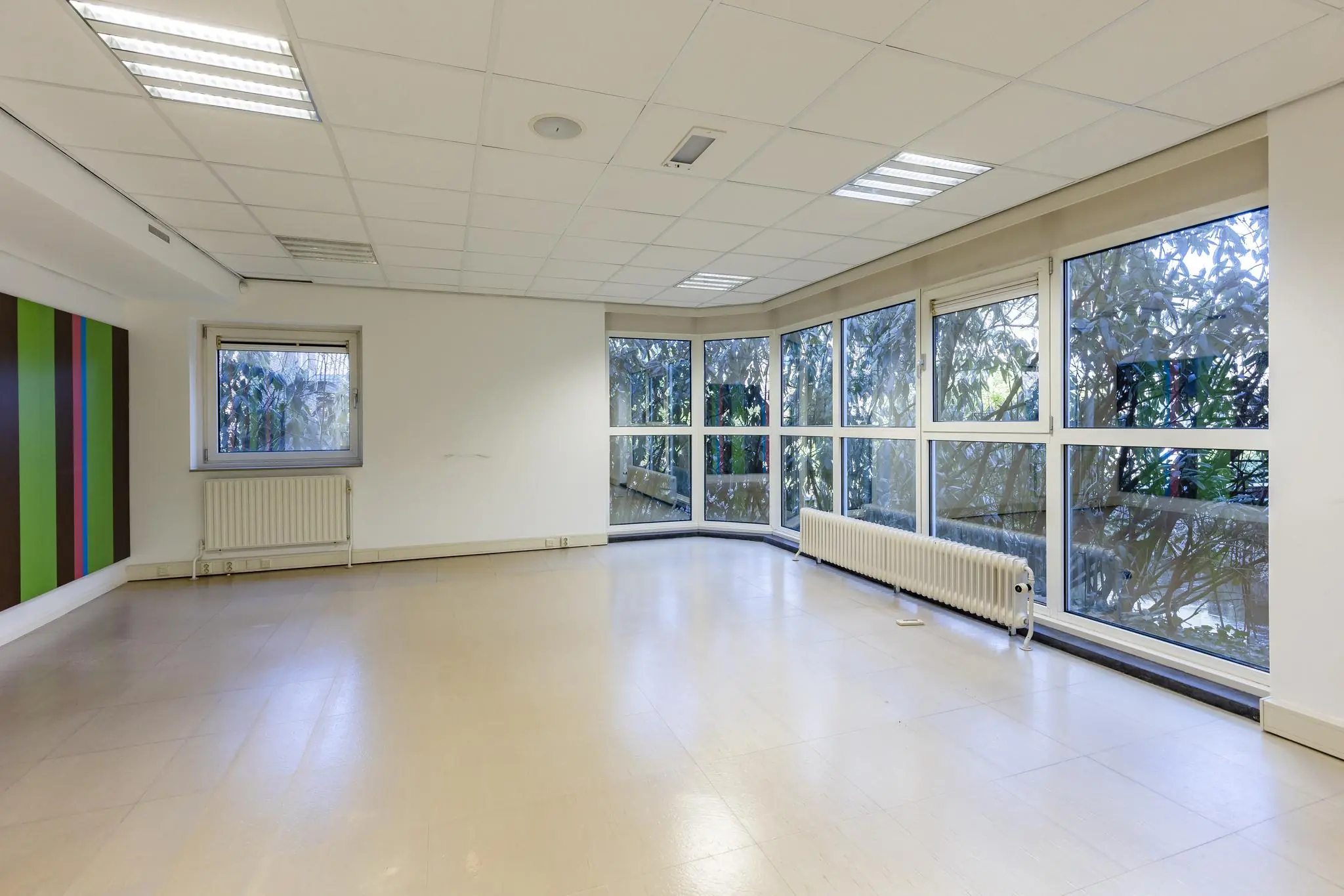 Lichte, lege kantoorruimte aan de ’s-Gravenweg met grote raampartijen en uitzicht op groen.