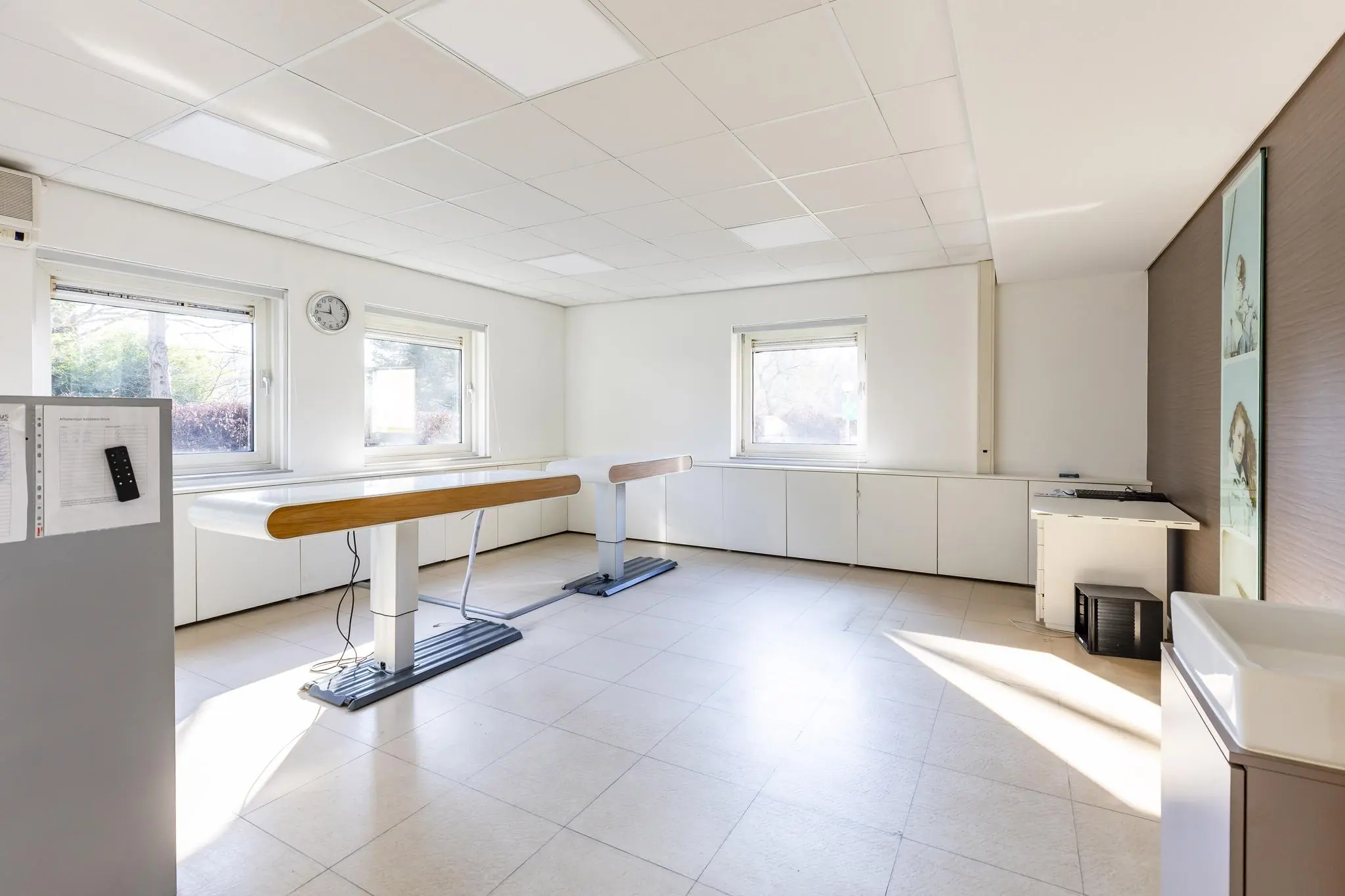 Lichte, moderne behandelruimte aan de 's-Gravenweg met twee behandelbanken en grote ramen.