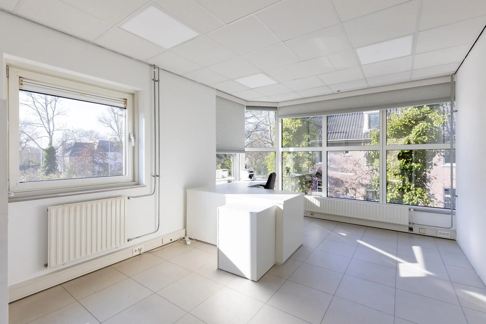 Licht en modern kantoor met witte meubels en grote ramen aan de 's-Gravenweg.