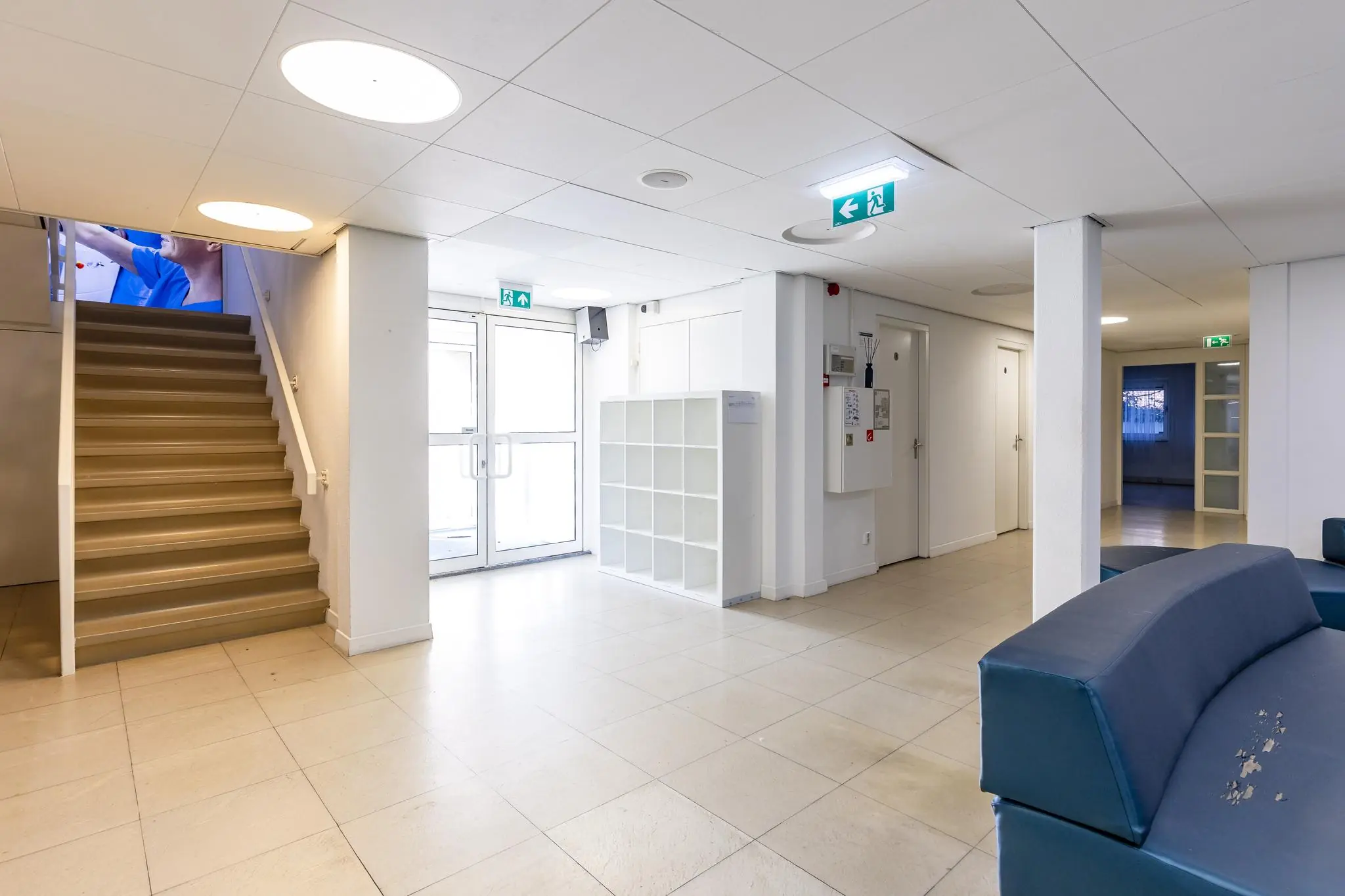 Moderne, lichte entreehal van een gebouw aan de 's-Gravenweg met trap, zitbanken en opbergvakken.