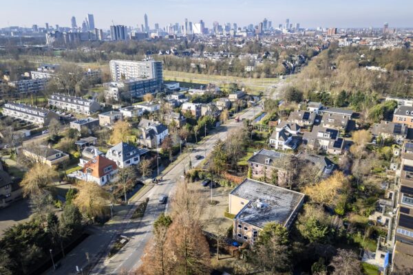 Luchtfoto van de ’s-Gravenweg in Rotterdam met woonhuizen op de voorgrond en de skyline van de stad op de achtergrond.