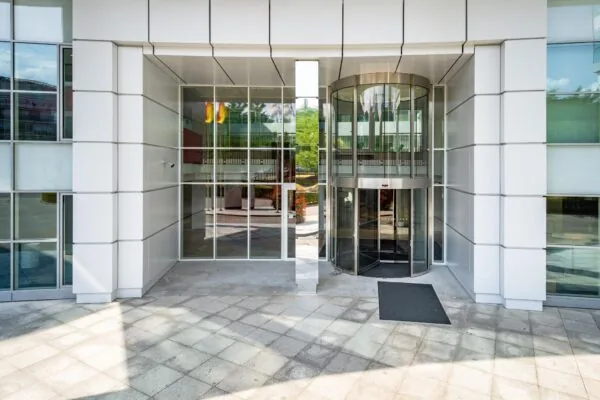 Ingang van een modern kantoorgebouw aan de Newtonlaan met een glazen draaideur en veel glaspartijen.