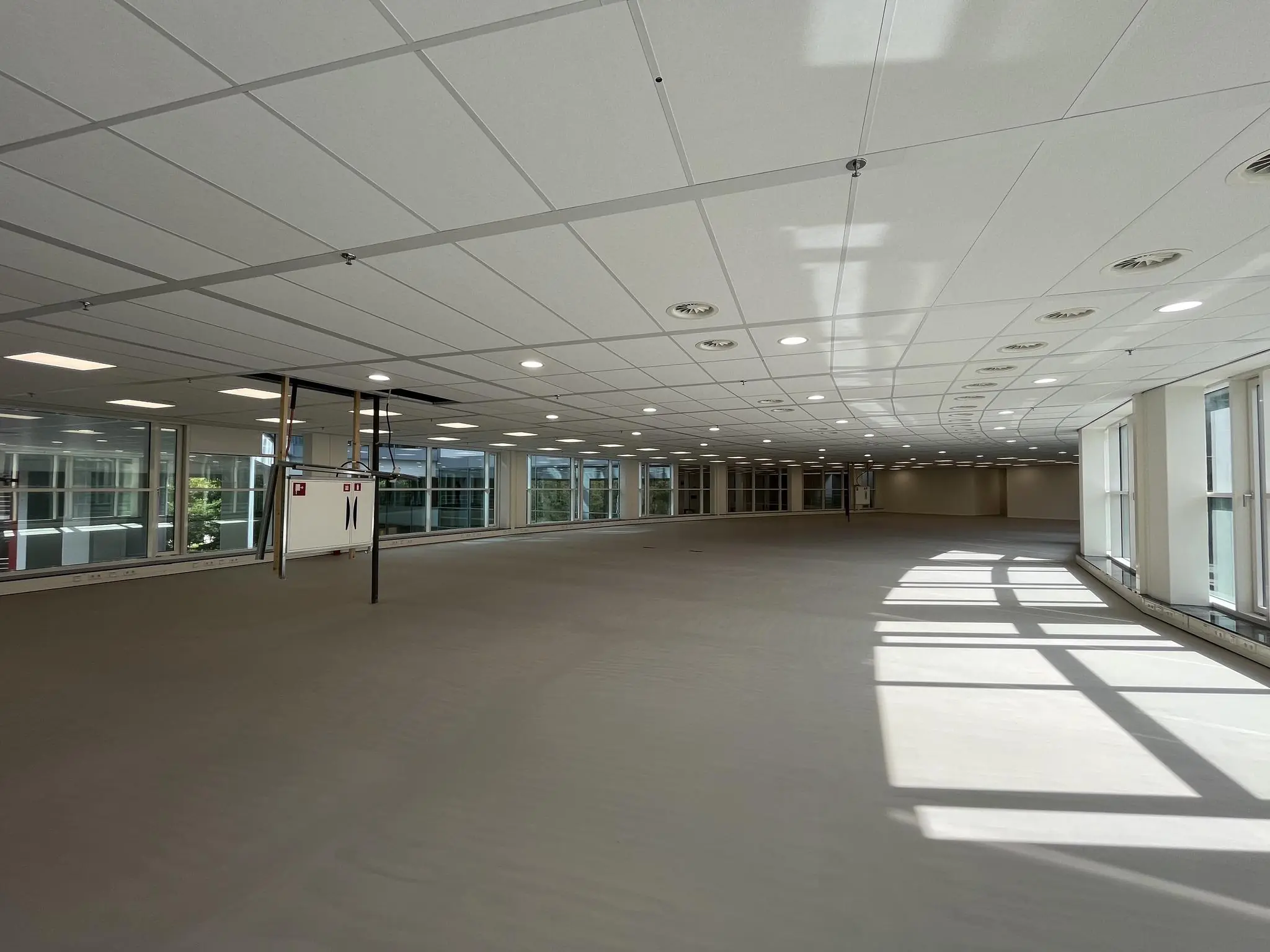 Leeg kantoorpand aan de Newtonlaan met grote ramen en systeemplafond.