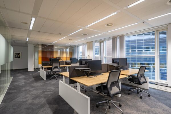 Moderne open kantoorruimte aan de Newtonlaan met werkplekken, bureaustoelen en computers.