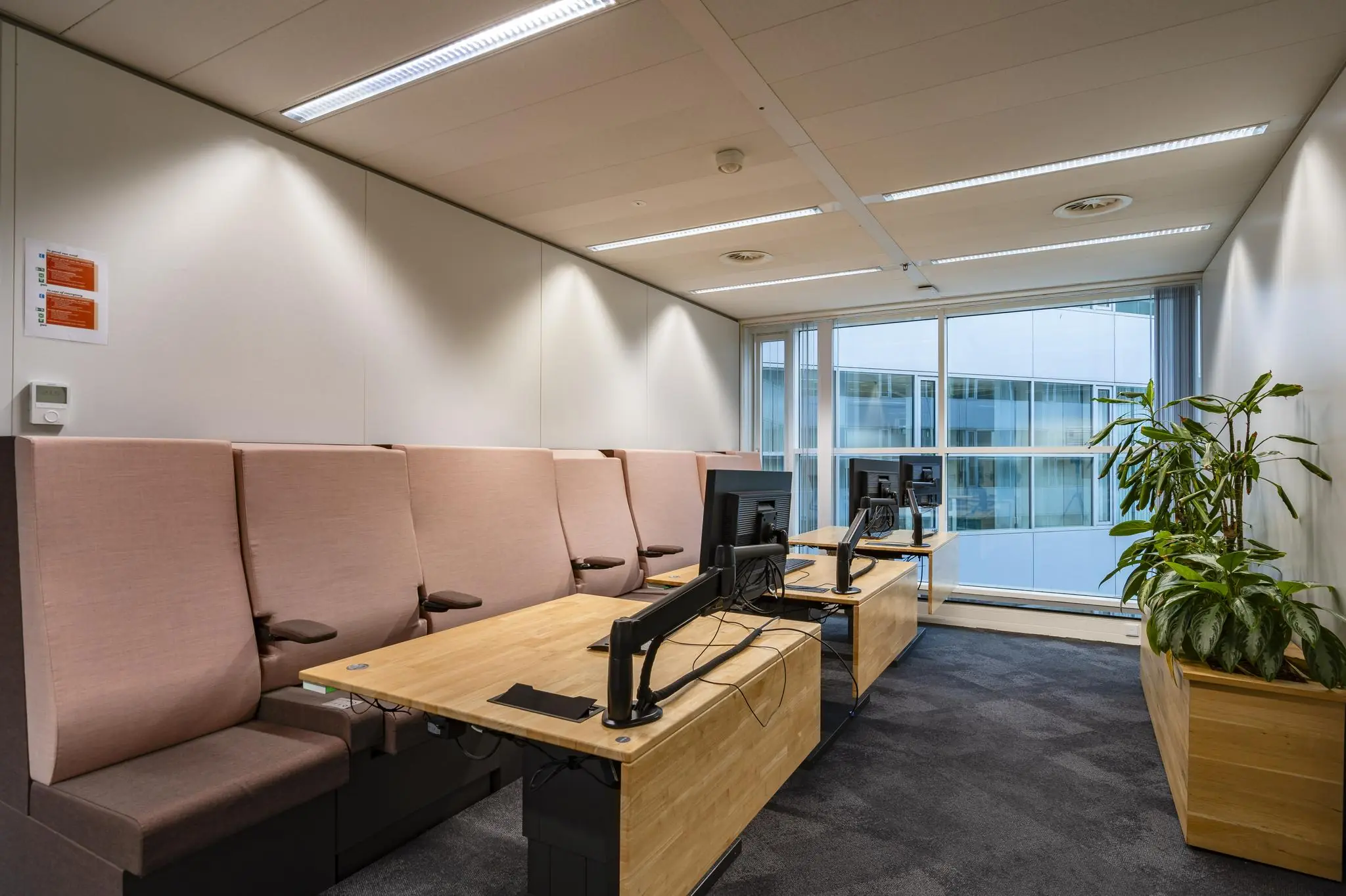 Moderne kantoorruimte aan de Newtonlaan met werkplekken, bureaustoelen, computers en planten bij het raam.