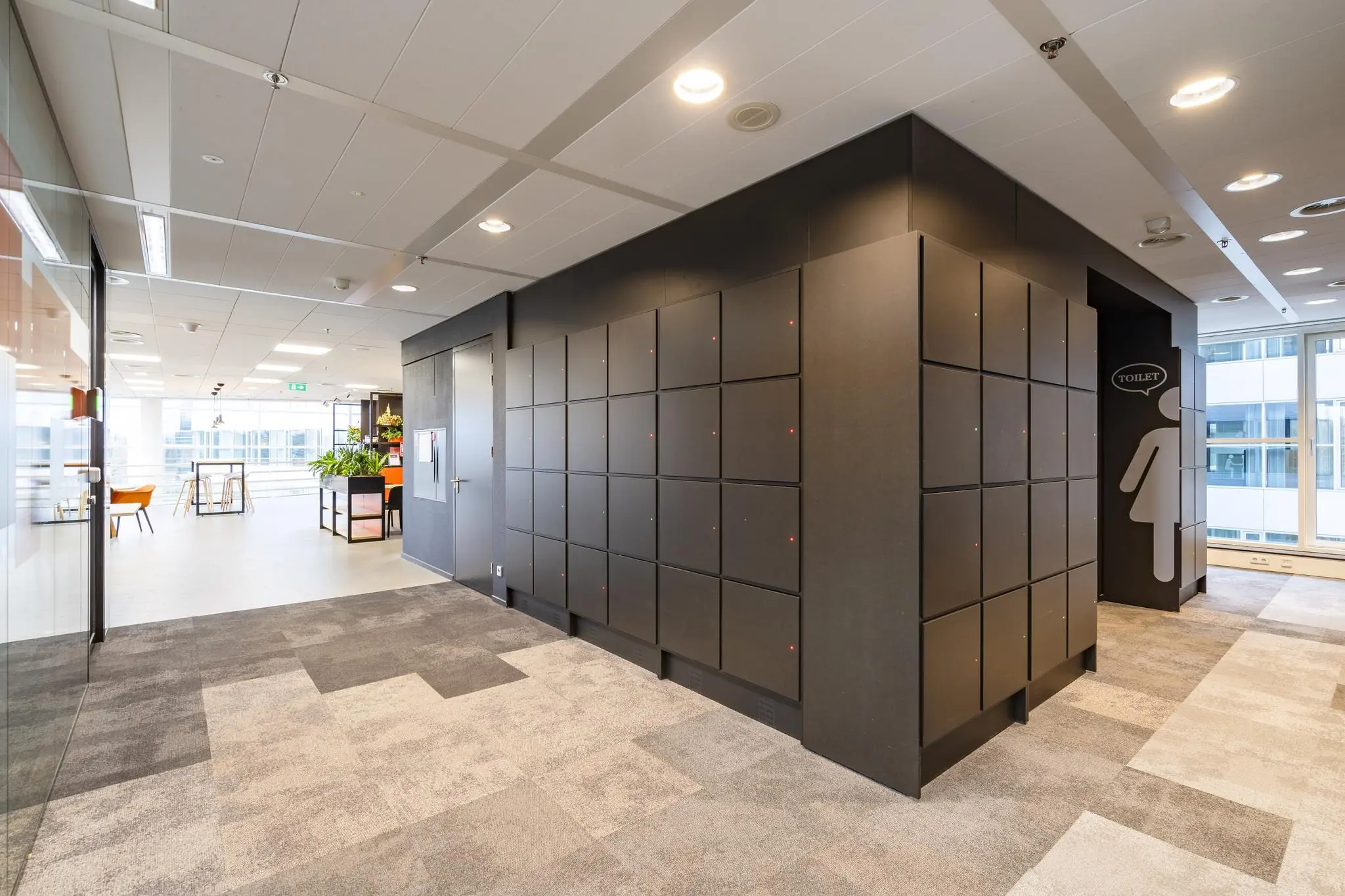 Moderne kantoorruimte aan de Newtonlaan met zwarte lockers, toiletruimte en zicht op een open werk- en zithoek.